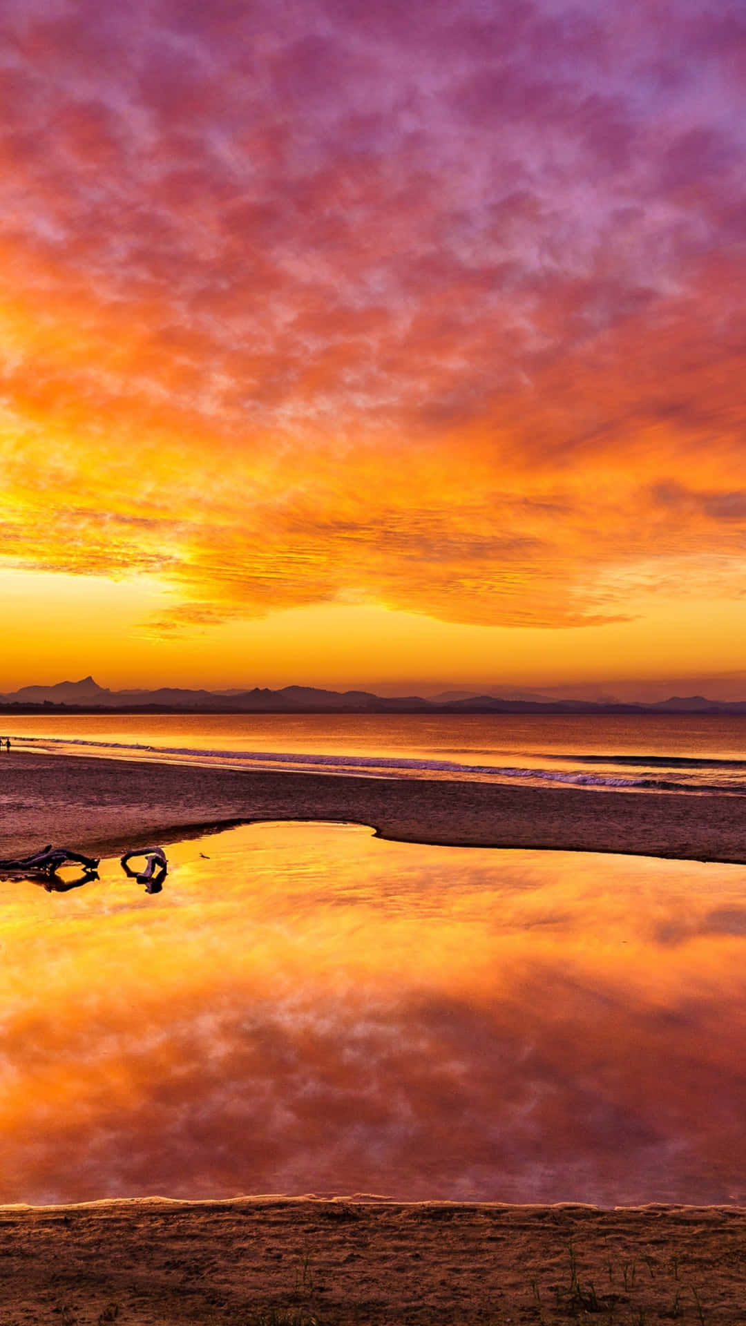 Hi Res Beach 桌布 壁紙 — 令人驚嘆的日落將天空染成火熱的橙色和紫色，完美地反射在寧靜海灘的潮汐池中。