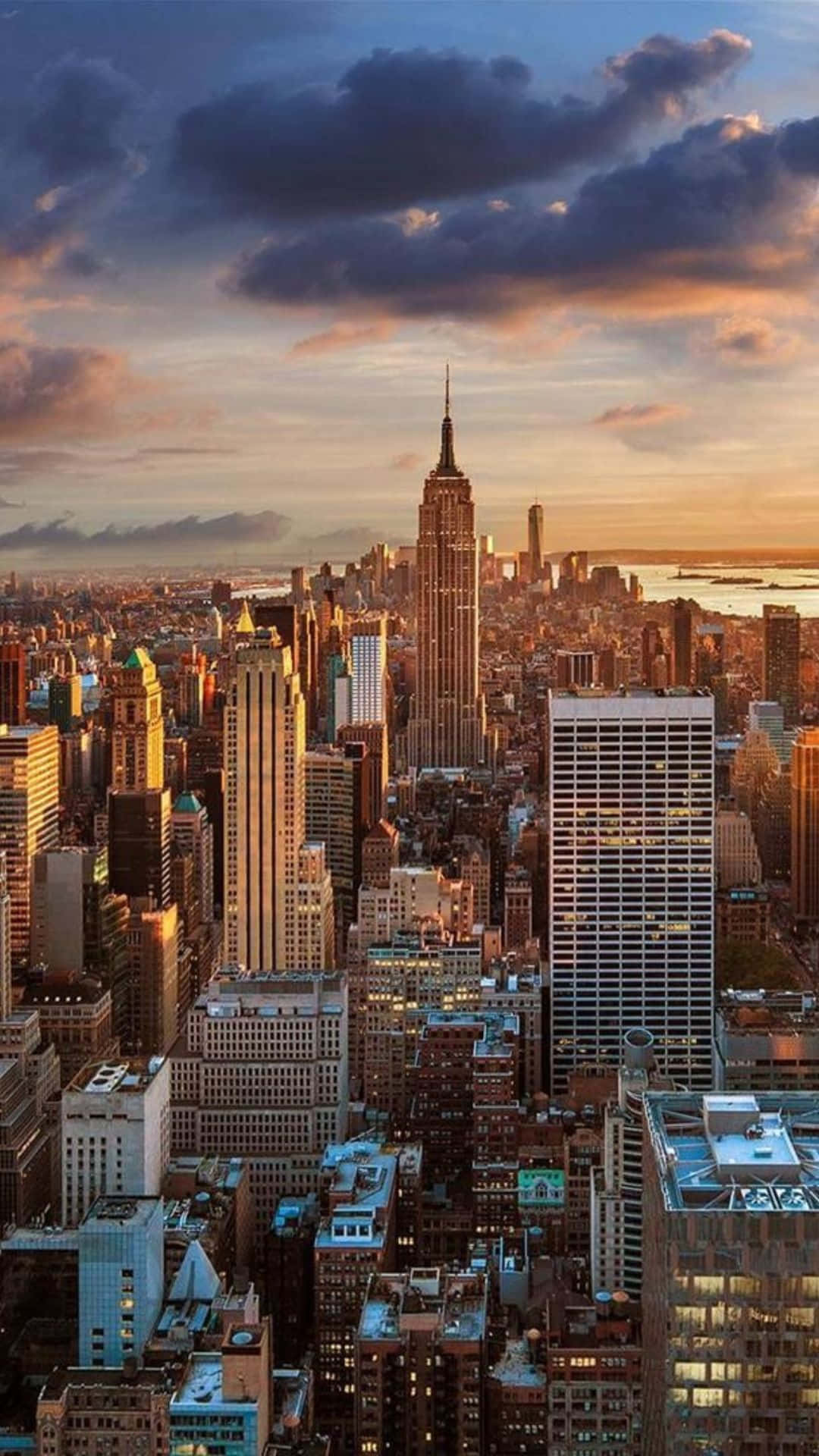 Android Ny City 桌布 壁紙 — 令人驚嘆的日落映照紐約市天際線，帝國大廈高聳於密集的城市建築之上。