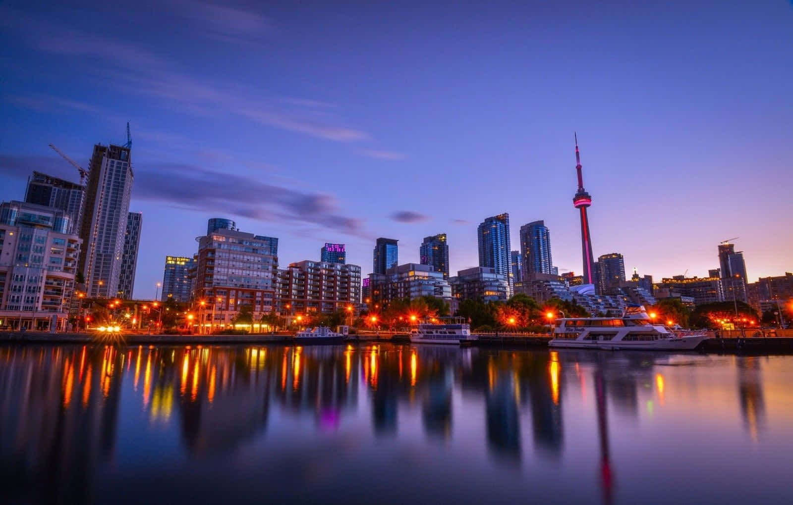 Toronto 桌布 壁紙 — 令人驚嘆的暮色城市景觀，燈火通明的摩天大樓和CN塔倒映在平靜的水面上。