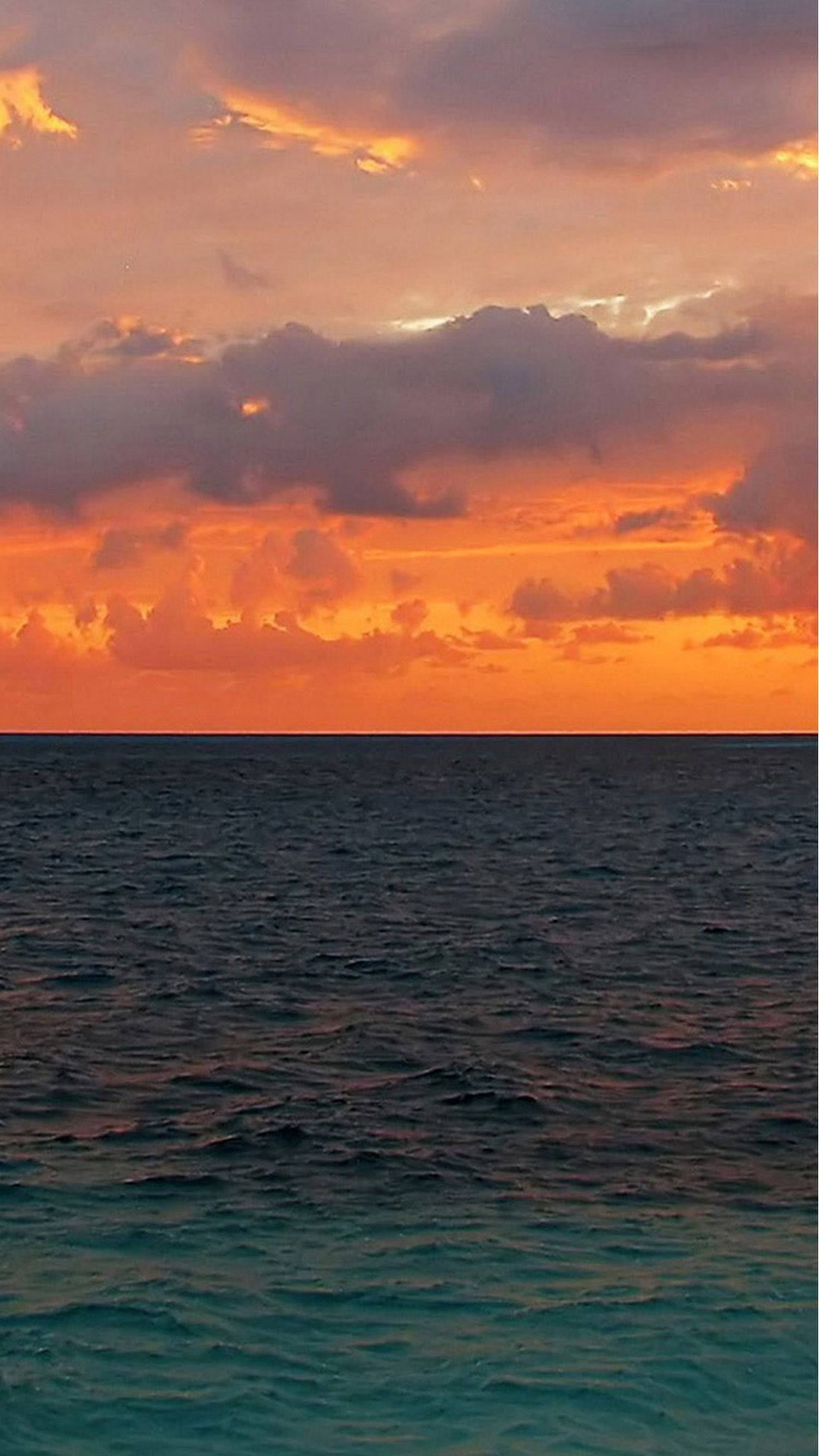 Sunset iPhone 桌布 壁紙 — 令人驚嘆的海洋日落，火紅的橙色雲彩倒映在碧綠的海水中。