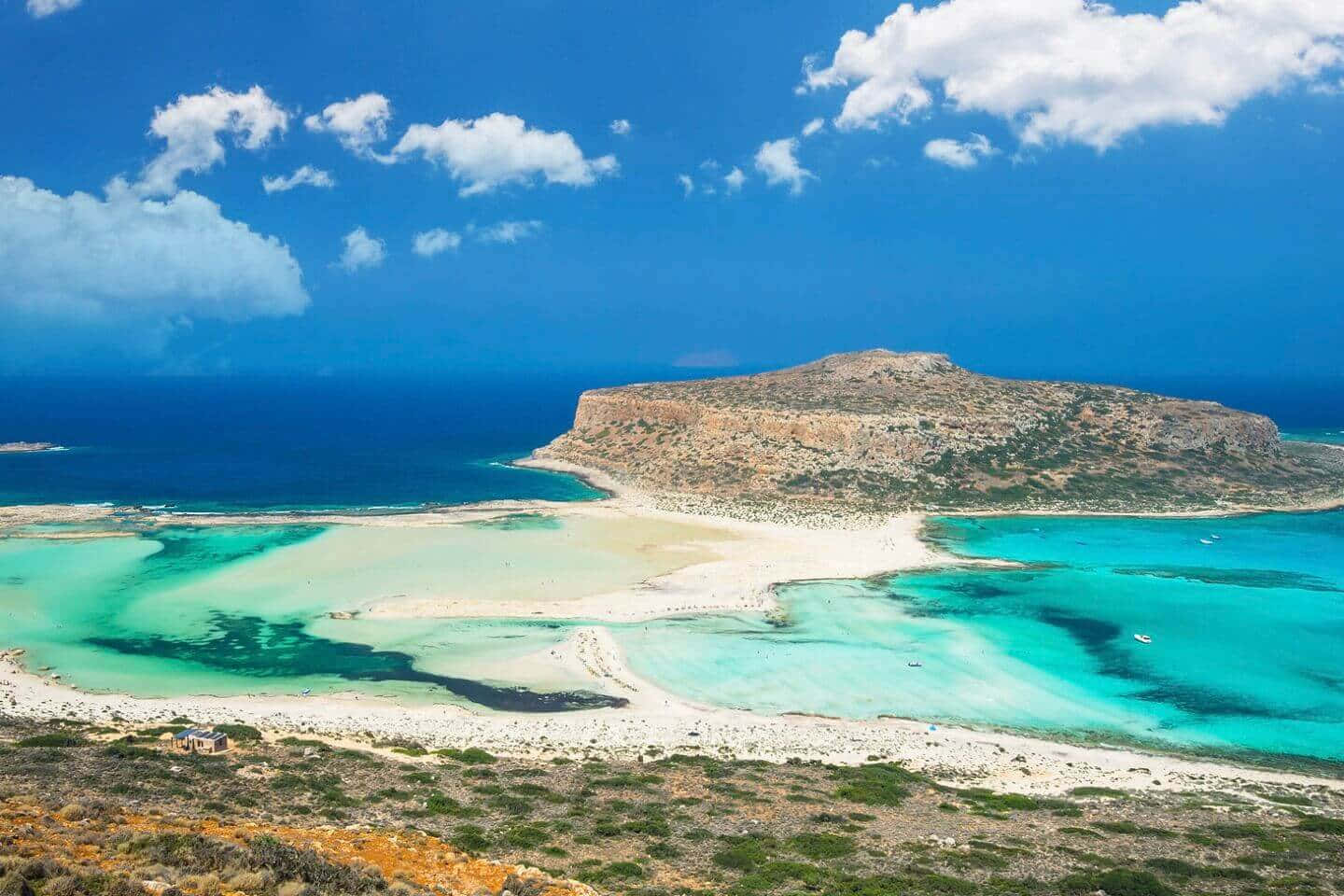 Greek Beach 桌布 壁紙 — 令人驚嘆的碧綠潟湖的鳥瞰圖，周圍環繞著白色沙灘和崎嶇的懸崖，在充滿活力的藍天和蓬鬆的雲彩下。
