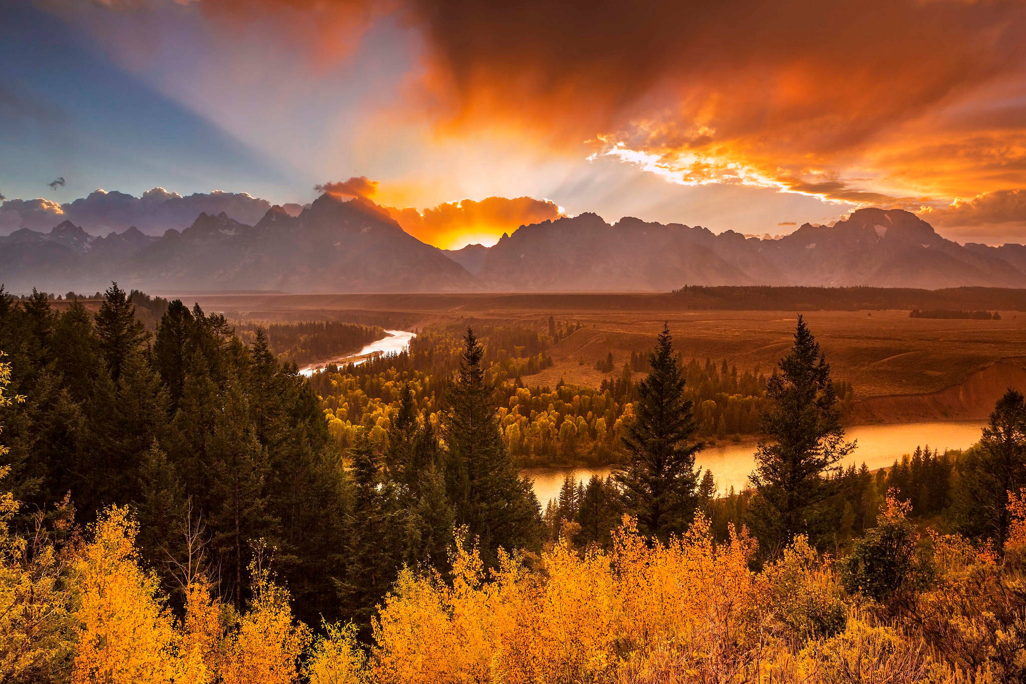 Yellowstone 桌布 壁紙 — 令人驚嘆的秋日落日，照耀著山脈，金色的白楊樹和蜿蜒的河流在下方。