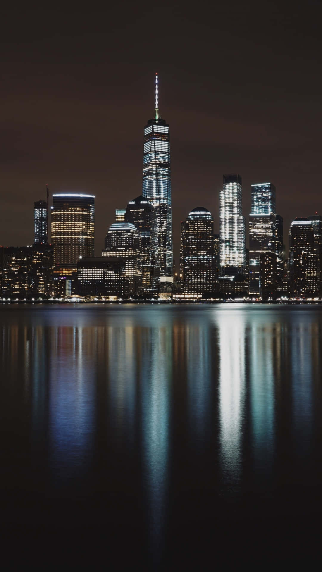 New York City Night iPhone 桌布 壁紙 — 令人驚嘆的紐約天際線夜景，倒映在平靜的水面上，摩天大樓燈火通明。