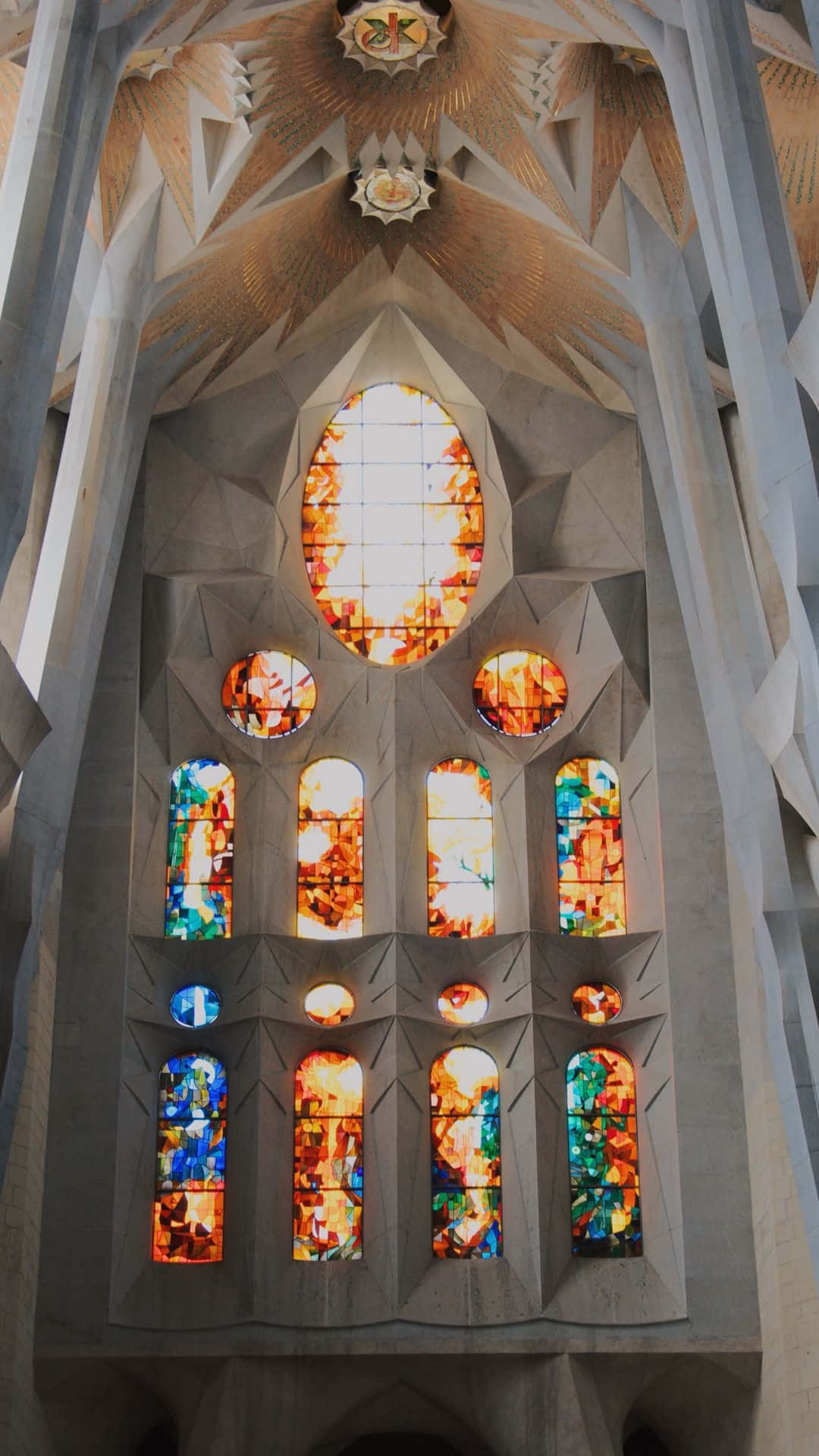 Barcelona 桌布 壁紙 — 令人驚嘆的聖家堂內部向上視角，展現精緻的石造建築和鮮豔的彩繪玻璃窗，讓空間沐浴在多彩的光線中。