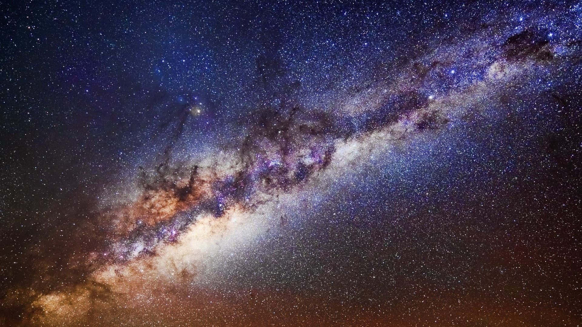 Real Galaxy 桌布 壁紙 — 令人驚嘆的銀河系景觀，橫跨佈滿星星的夜空，帶有鮮豔的紫色和橙色星雲。