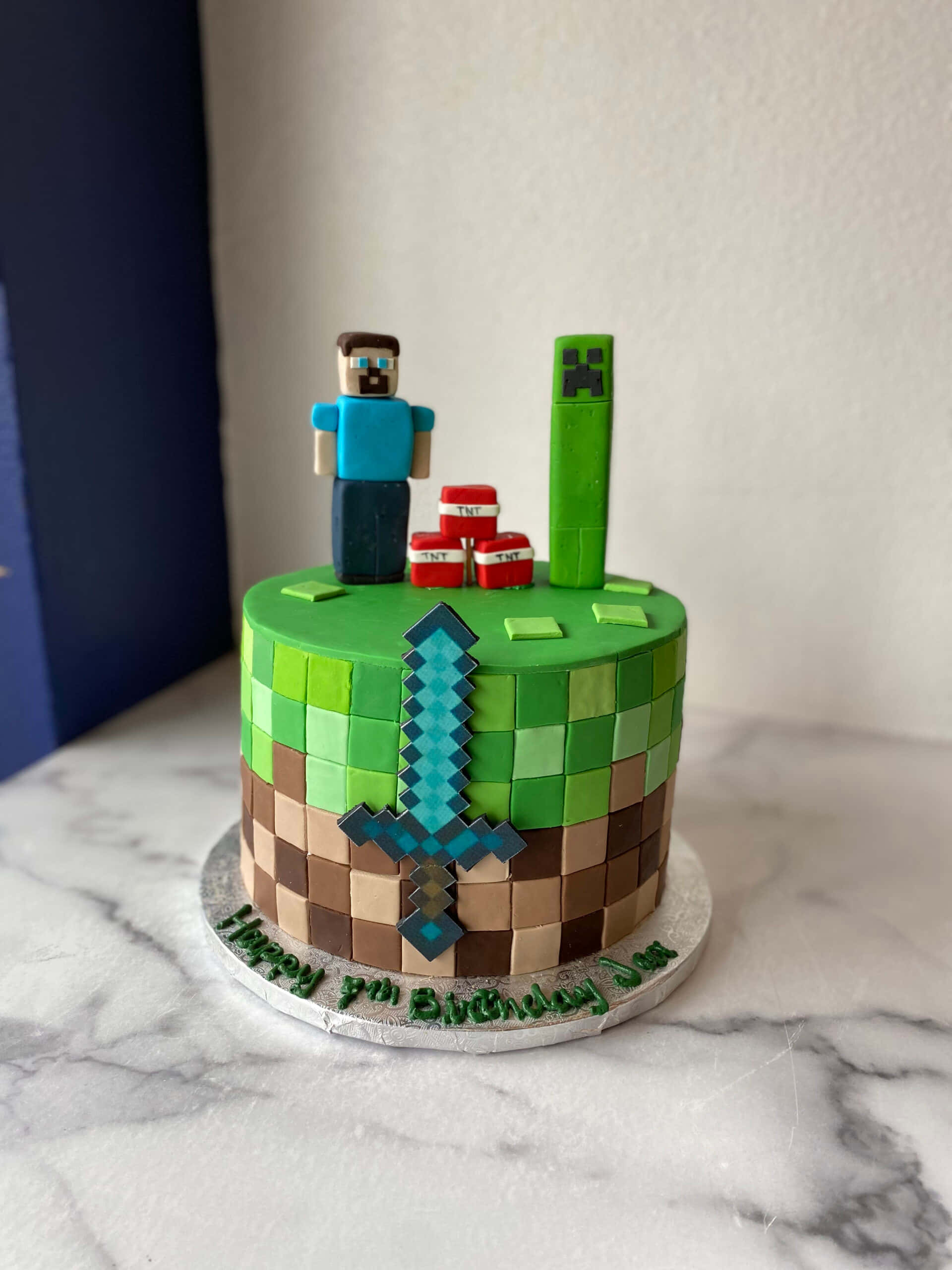 Minecraft Cakes 桌布 壁紙 — 以像素化 Steve 和 Creeper 裝飾、鑽石劍和草塊設計為主題的 Minecraft 生日蛋糕。