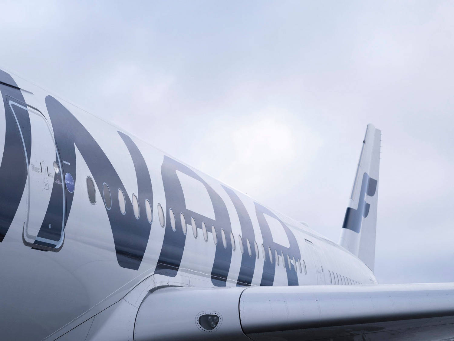 飛機 桌布 壁紙 — 以明亮多雲天空為背景的卡塔爾航空飛機機身低角度視圖。