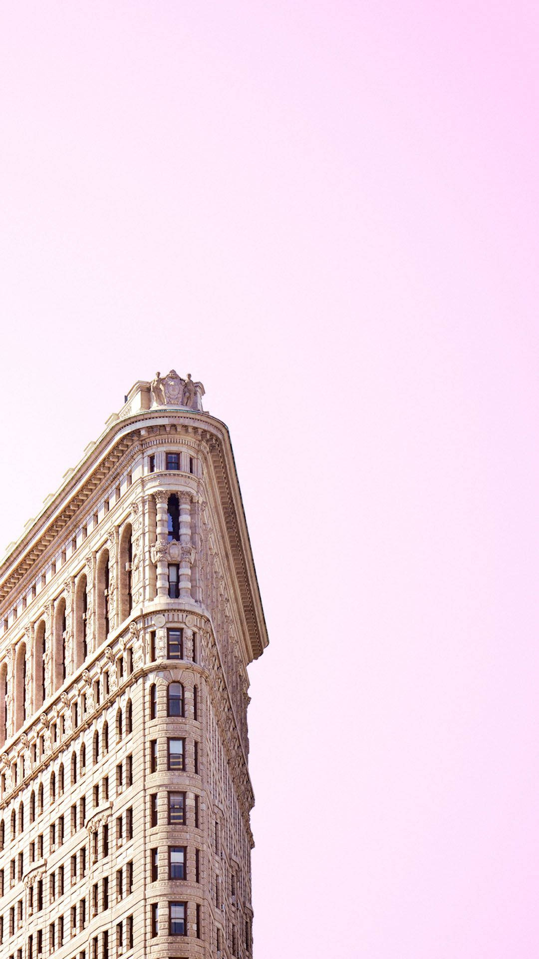 new york city iPhone x 桌布 壁紙 — 以柔和粉紅色天空為背景的標誌性熨斗大廈低角度景觀。