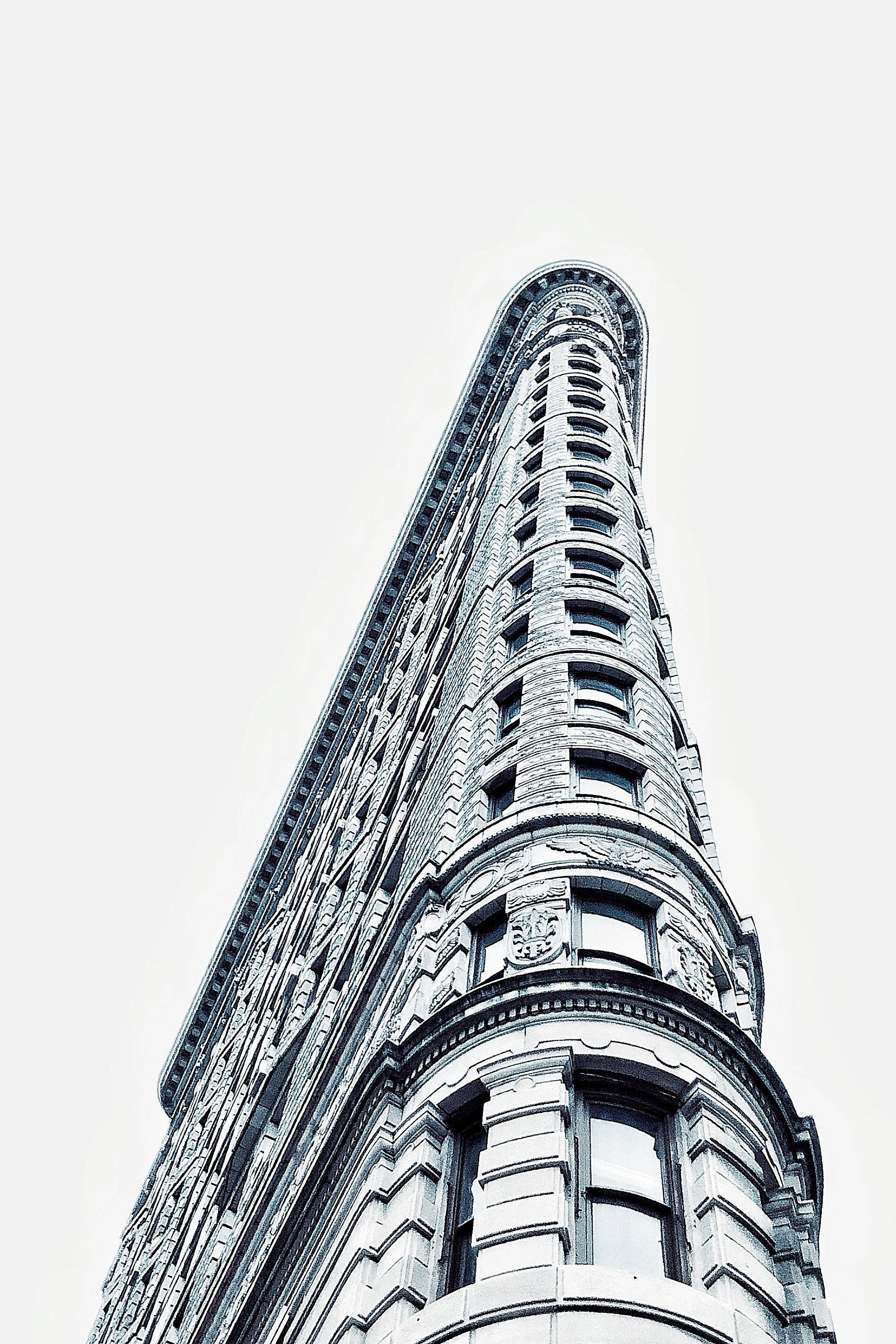 Flatiron Building 桌布 壁紙 — 以淡色天空為背景，紐約市標誌性熨斗大廈的戲劇性低角度景觀。