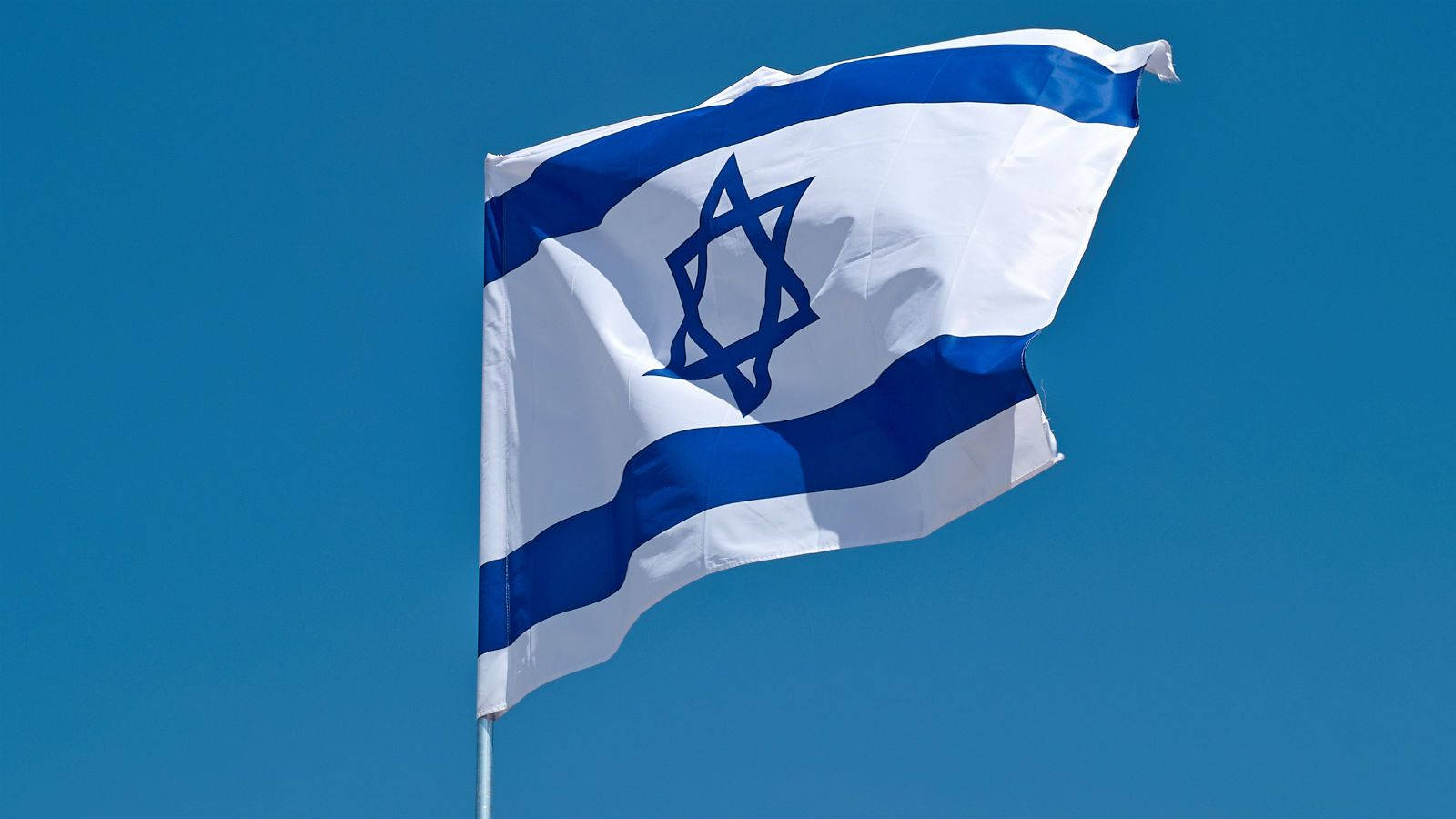 Israel Flag 桌布 壁紙 — 以色列國旗上的藍色大衛之星和條紋在清澈的蔚藍天空中動態飄揚。