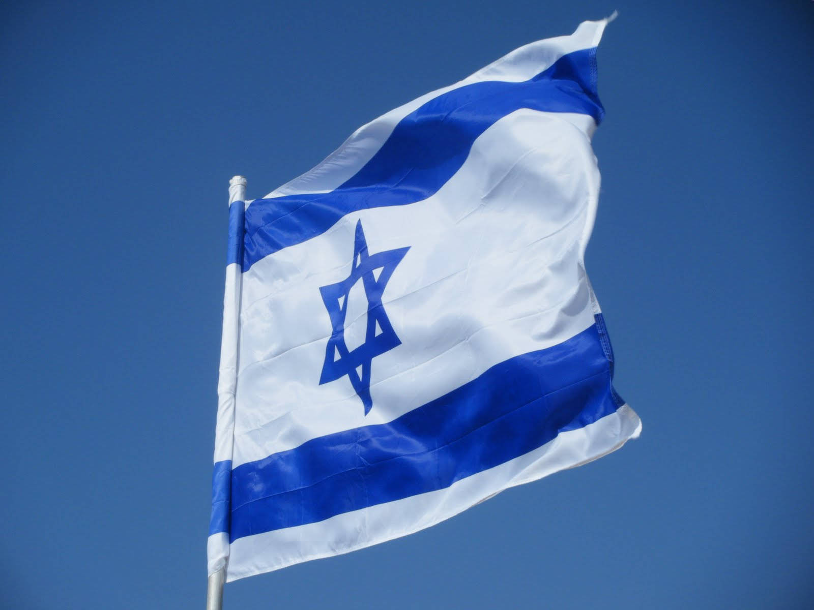 Israel Flag 桌布 壁紙 — 以色列國旗帶有藍白條紋和大衛之星，在清澈的藍天下動態飄揚。