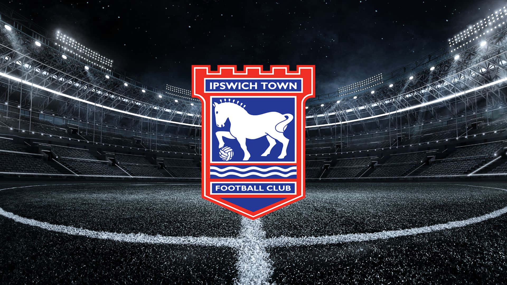 Ipswich Town 桌布 壁紙 — 伊普斯維奇足球俱樂部徽章在星空和明亮泛光燈下的空蕩球場中央閃耀。
