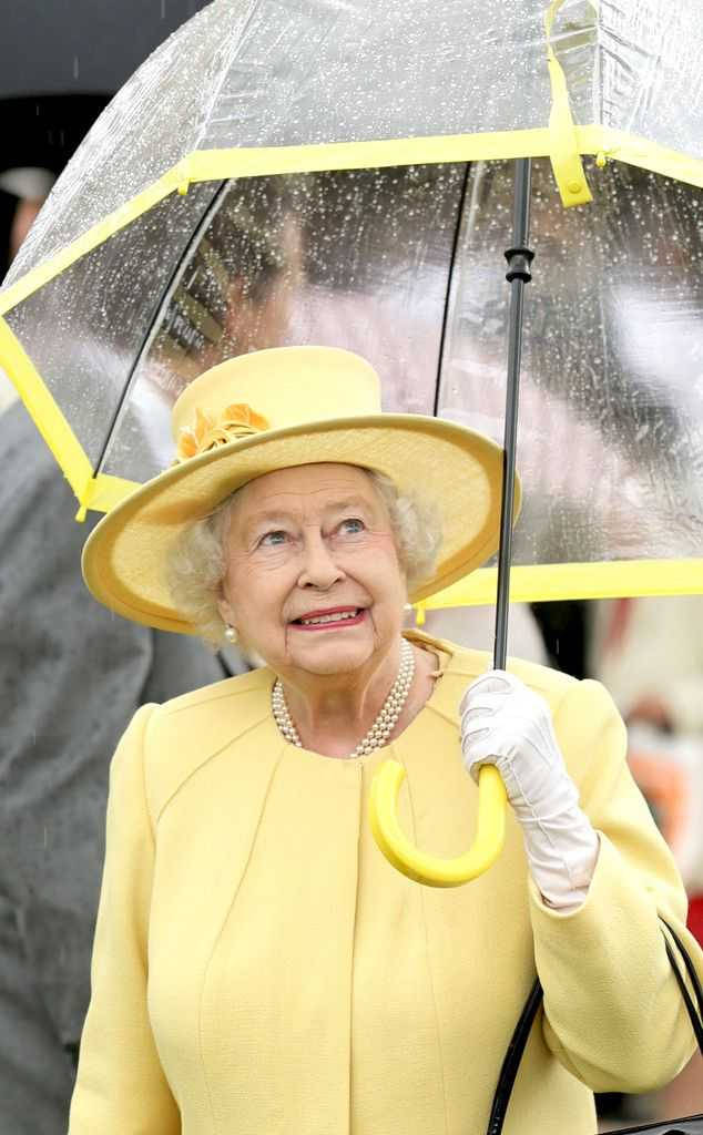 Queen Elizabeth 桌布 壁紙 — 伊莉莎白二世女王在雨天手持黃色雨傘，穿著相配的黃色服裝和帽子，溫暖地微笑。