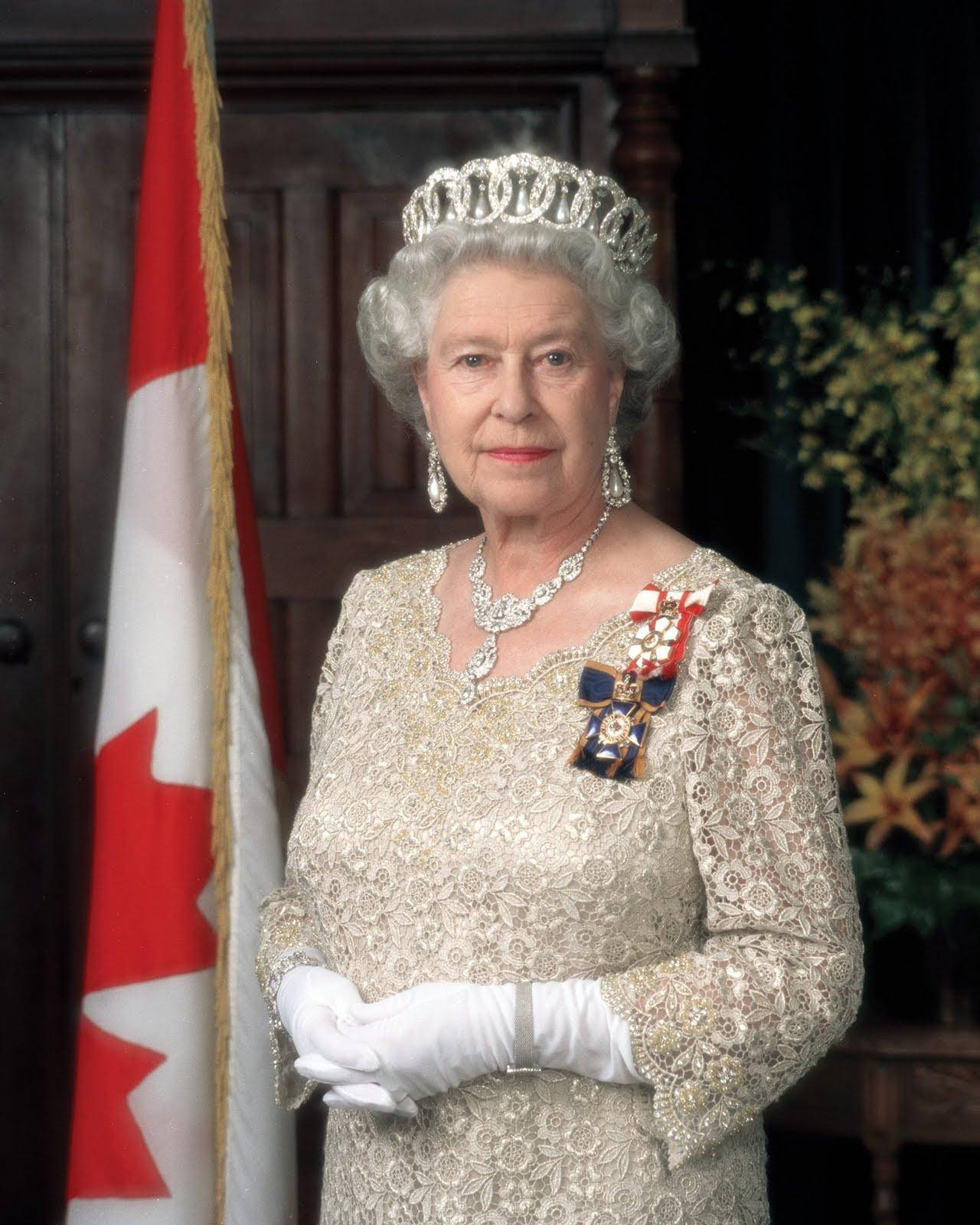 Queen Elizabeth 桌布 壁紙 — 伊莉莎白二世女王身穿金色蕾絲長裙、佩戴鑽石冠冕，莊嚴地站在加拿大國旗旁，這是一幅正式肖像。