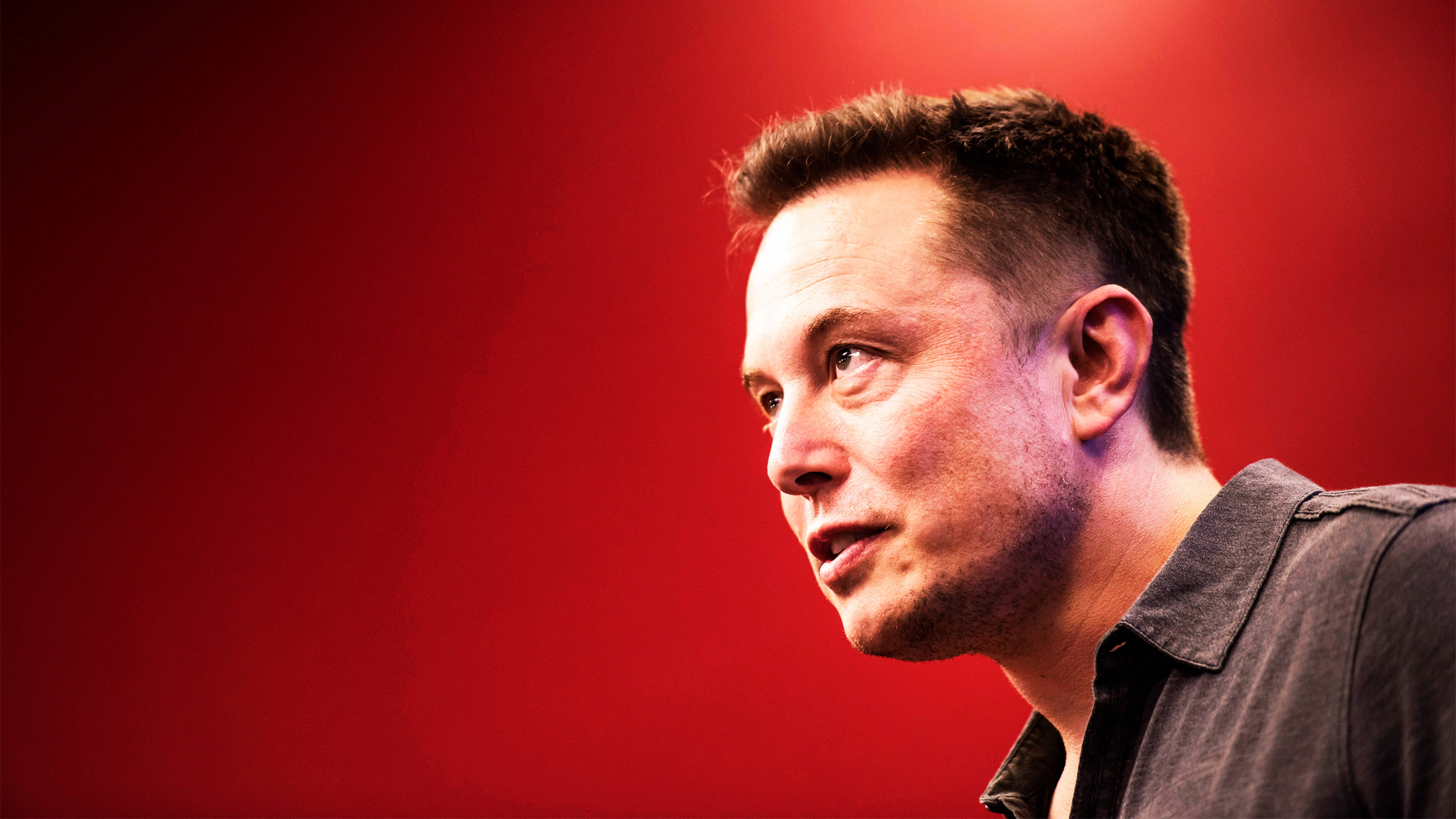 Elon 桌布 壁紙 — 伊隆·馬斯克側面像，背景為鮮豔的紅色，戲劇性的燈光凸顯他專注的表情。