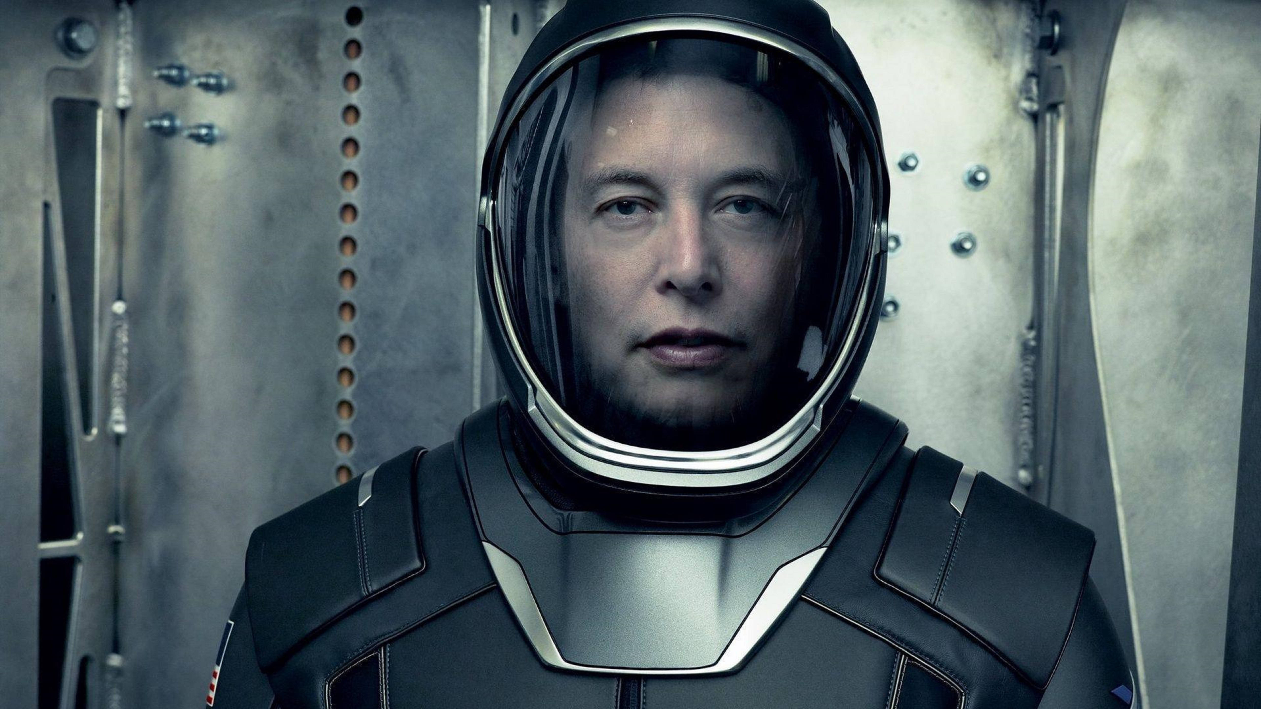 Elon 桌布 壁紙 — 伊隆·馬斯克穿著未來派太空人服裝，在金屬太空船內部透過頭盔面罩專注地凝視。