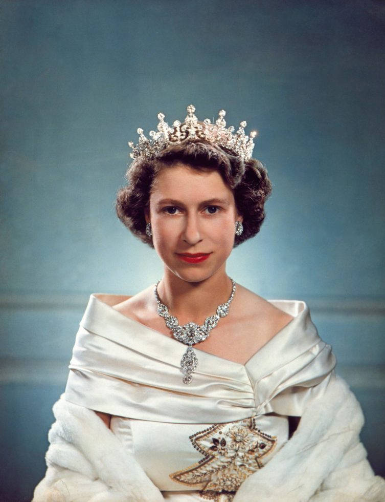 Queen Elizabeth 桌布 壁紙 — 伊麗莎白二世女王的尊貴肖像，佩戴閃爍鑽石头飾項鍊，身穿白色緞面長袍，背景為柔和的藍色。