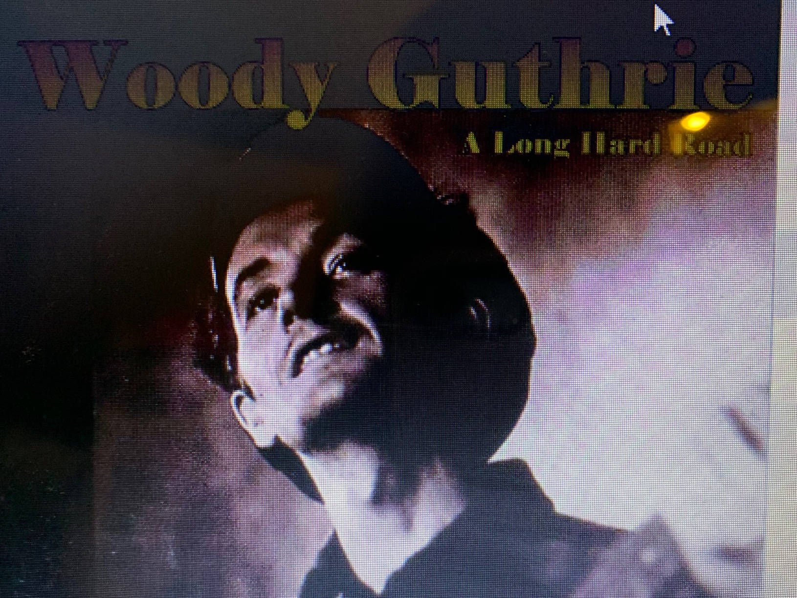 黑白 桌布 壁紙 — 伍迪·格思里（Woody Guthrie）的戲劇性肖像，在煙霧繚繞的背景中向上凝視，表情強烈。
