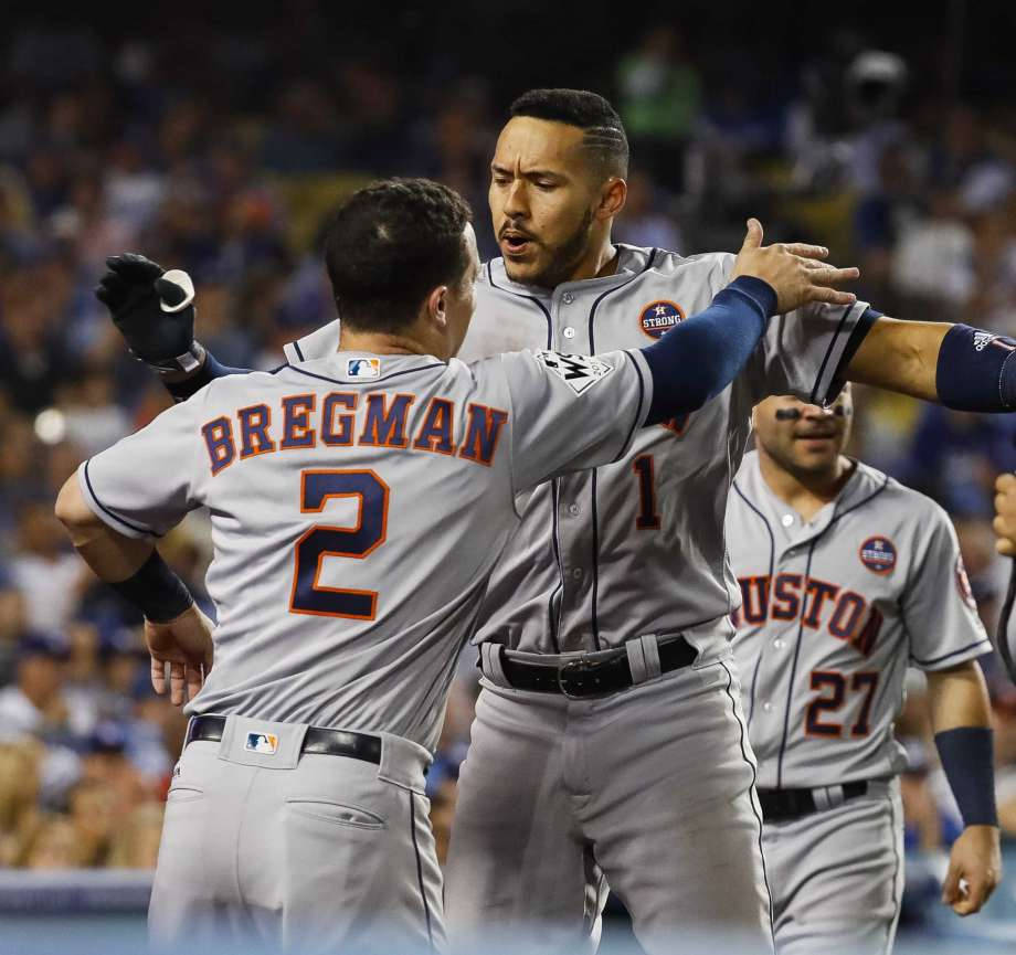 Bregman 桌布 壁紙 — 休士頓太空人棒球球員在球場燈光下以擊掌和激烈的表情慶祝一個比賽。