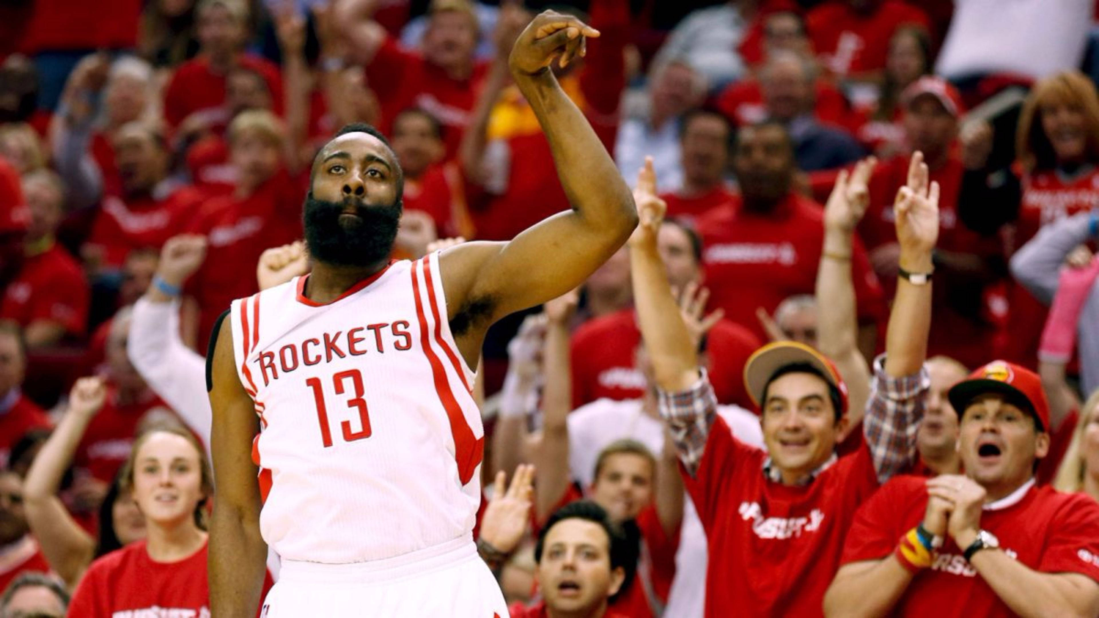 4K NBA 桌布 壁紙 — 休士頓火箭隊13號球員高舉拳頭慶祝，身穿紅色球衣的熱情球迷在擠滿的場館中為他歡呼。