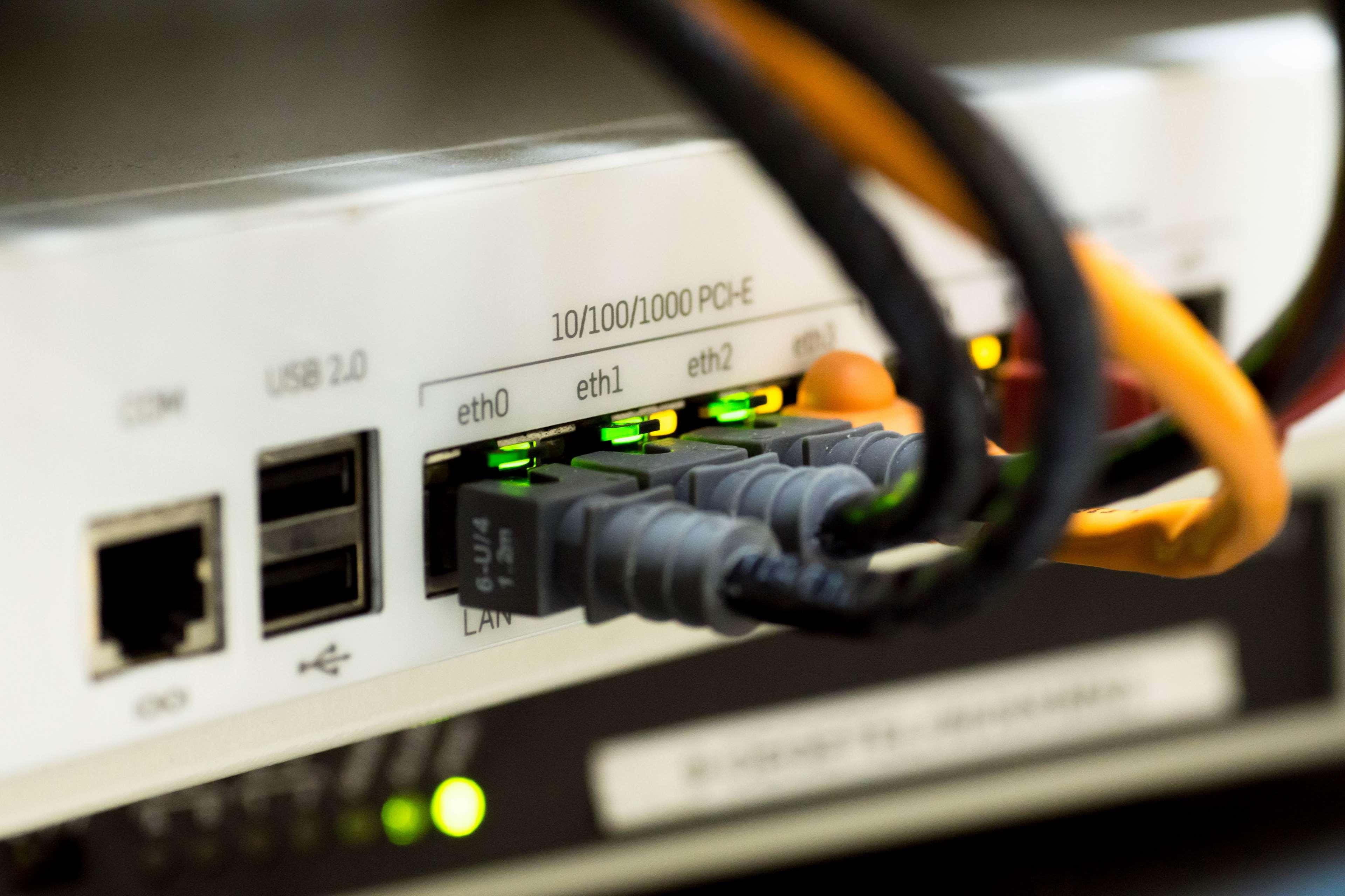 Ethernet 桌布 壁紙 — 伺服器機架特寫，帶有發光的綠色乙太網路埠和彩色纜線插入。