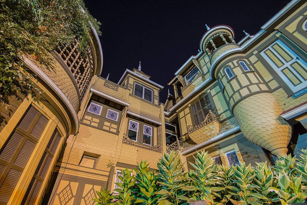 Mansion 桌布 壁紙 — 低角度夜拍捕捉了華麗的維多利亞式房屋，帶有精緻的木工和發光的窗戶，在星空下。