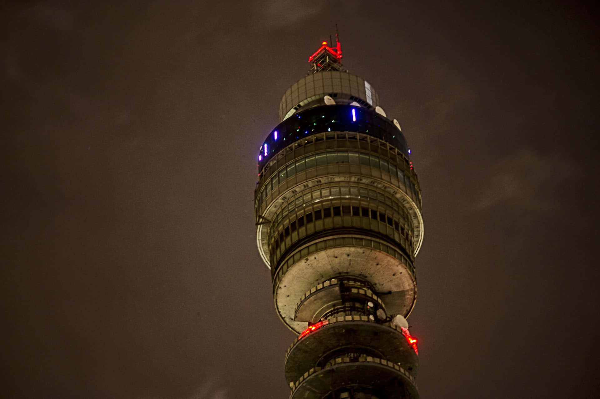 tower 桌布 壁紙 — 低角度夜攝雪梨塔眼，藍紅燈光映照在陰暗多雲的天空下。