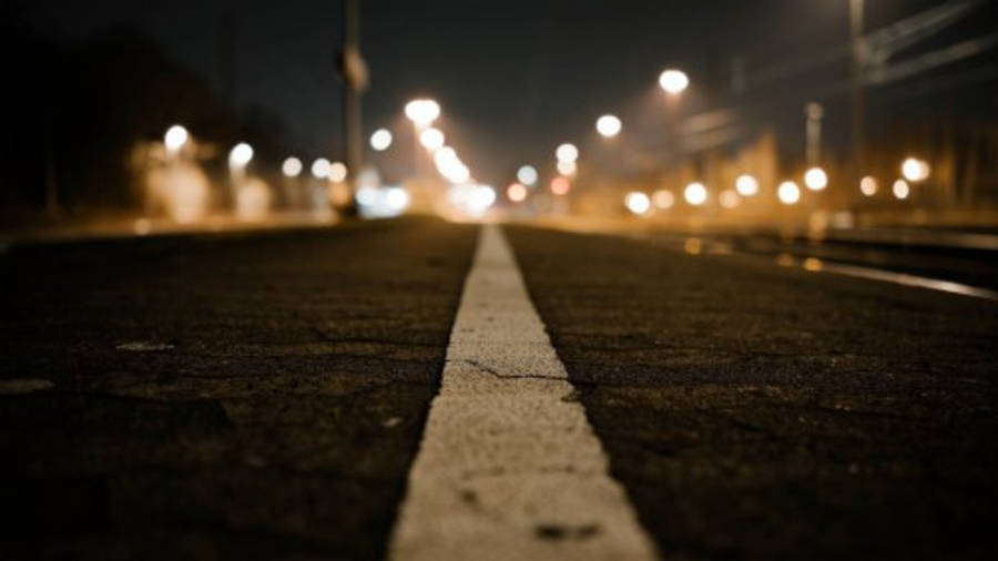 Road 桌布 壁紙 — 低角度夜間拍攝，一條裂開的道路，白色線條通向柔和散景中發光的街燈。