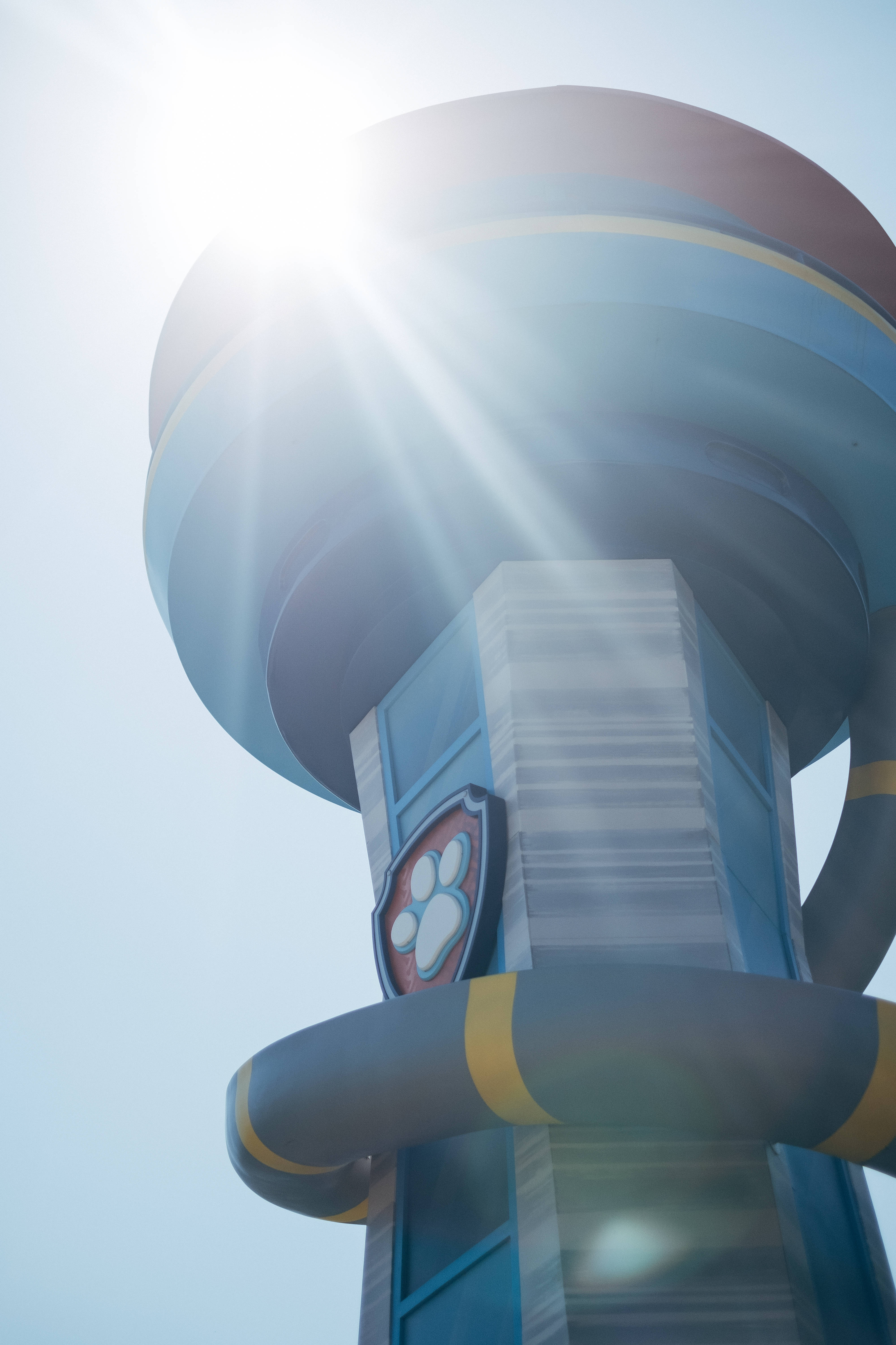 汪汪隊立大功 桌布 壁紙 — 低角度拍攝 Paw Patrol 瞭望塔，太陽在其藍黃條紋圓頂後方閃耀。