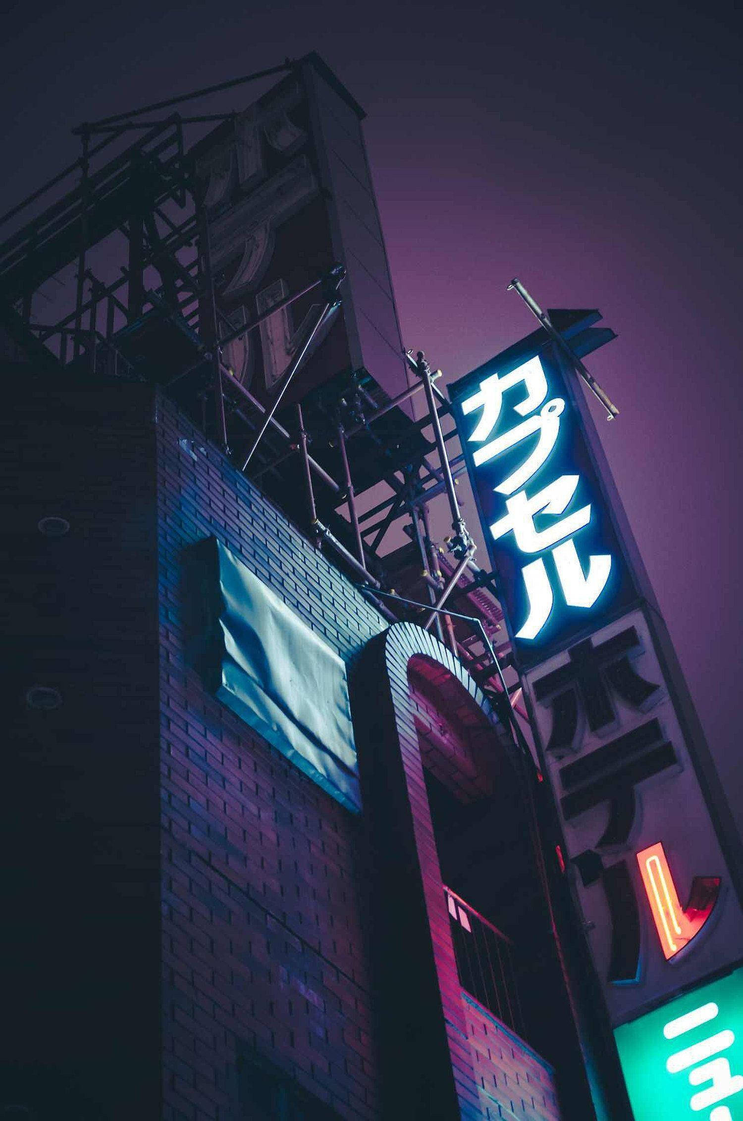 Japanese Aesthetic 桌布 壁紙 — 低角度拍攝，霓虹燈照亮的日本飯店招牌在磚造建築上，映襯著深紫色的夜空。