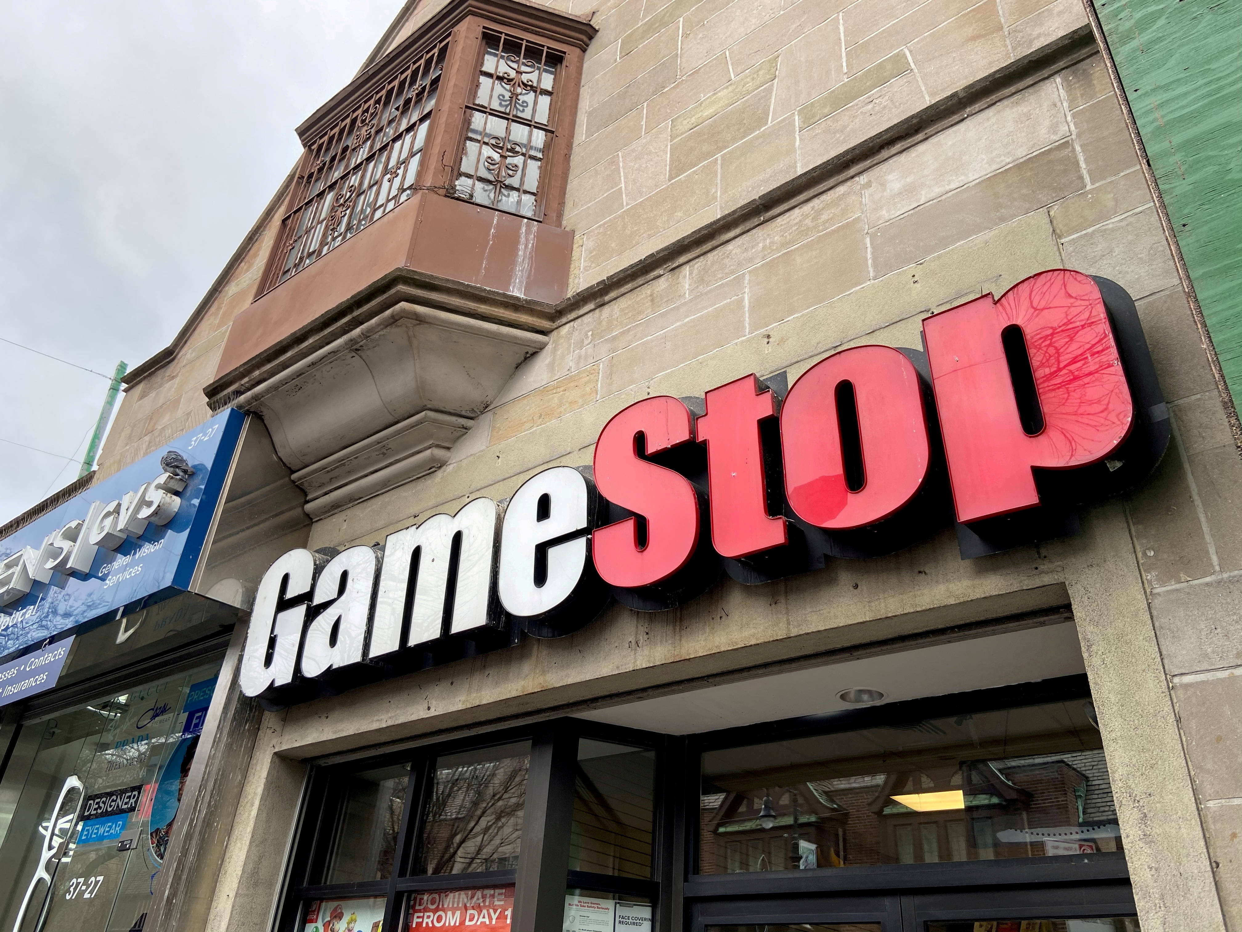 GameStop 桌布 壁紙 — 低角度拍攝GameStop商店招牌安裝在石建築物上，天空多雲。