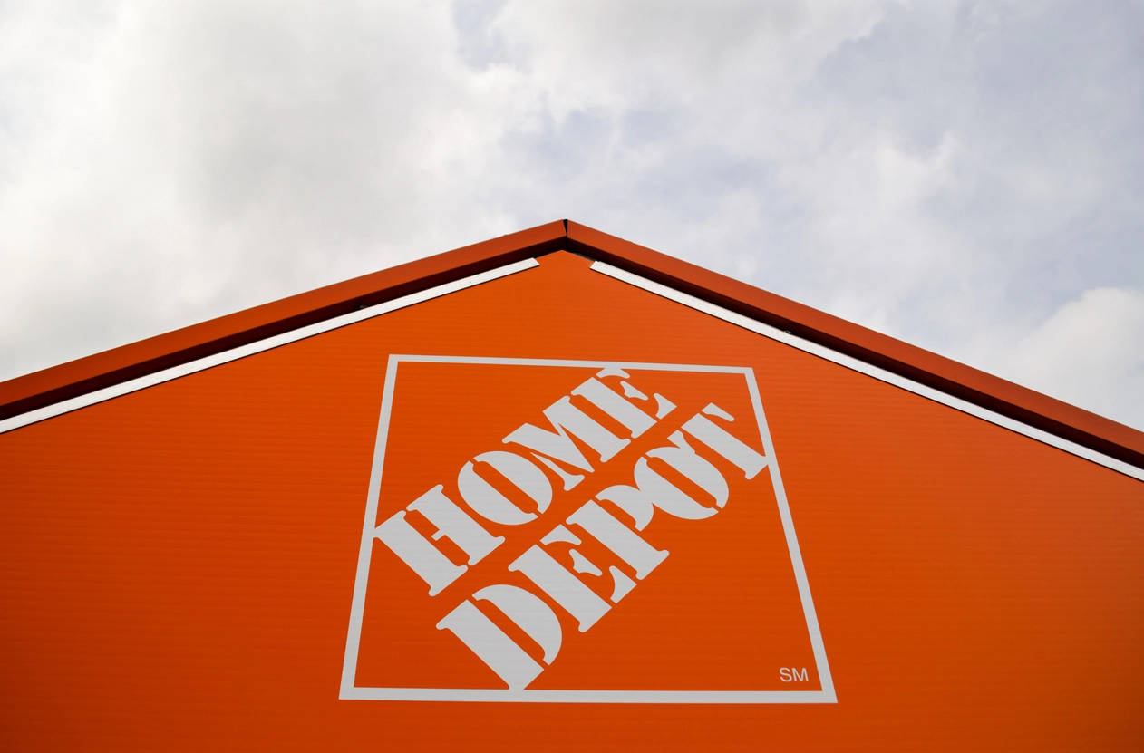Home Depot 桌布 壁紙 — 低角度拍攝Home Depot商店標誌性的橙色屋頂，帶有白色標誌，背景為多雲天空。