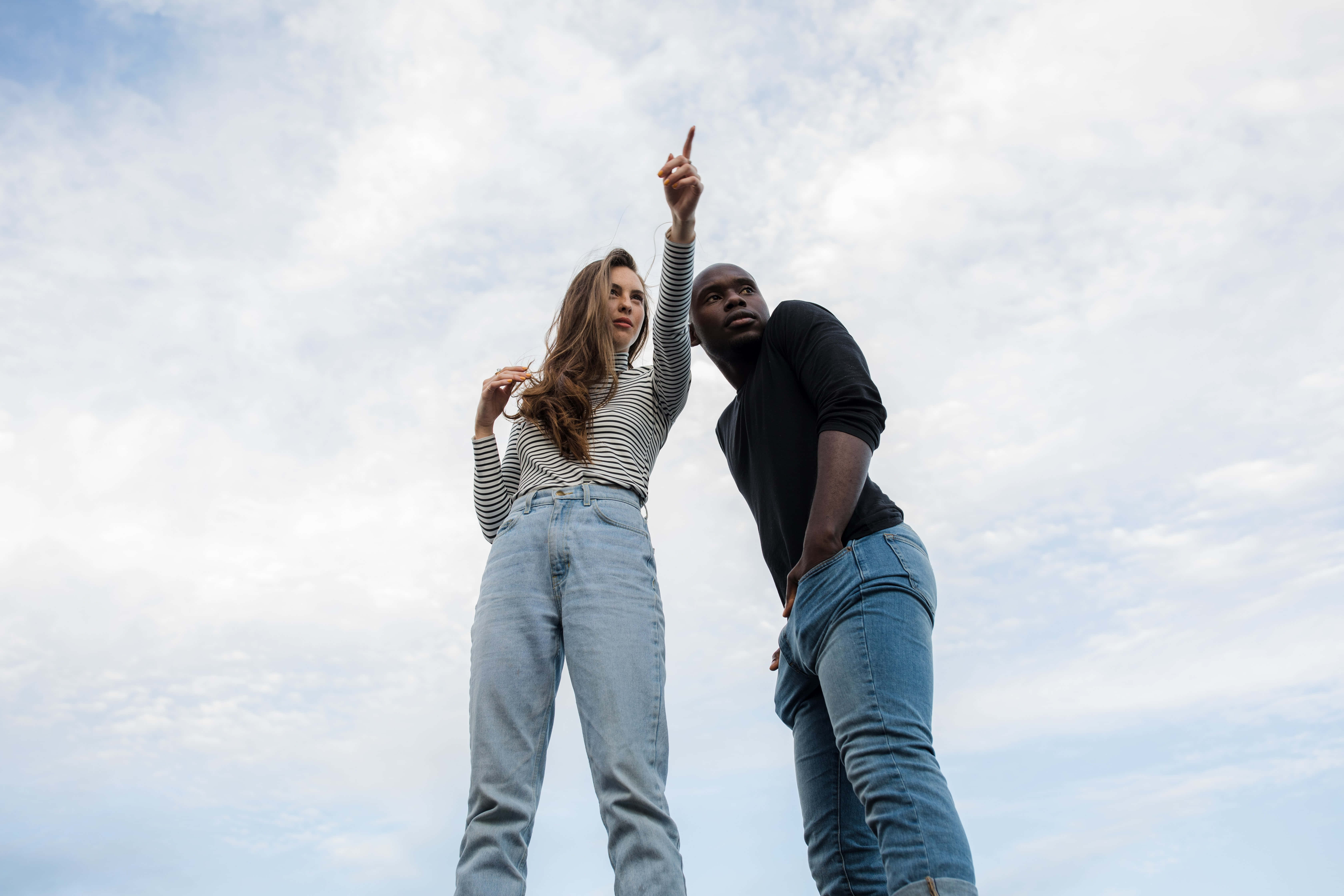 Interracial 桌布 壁紙 — 低角度拍攝一男一女指向多雲的天空。