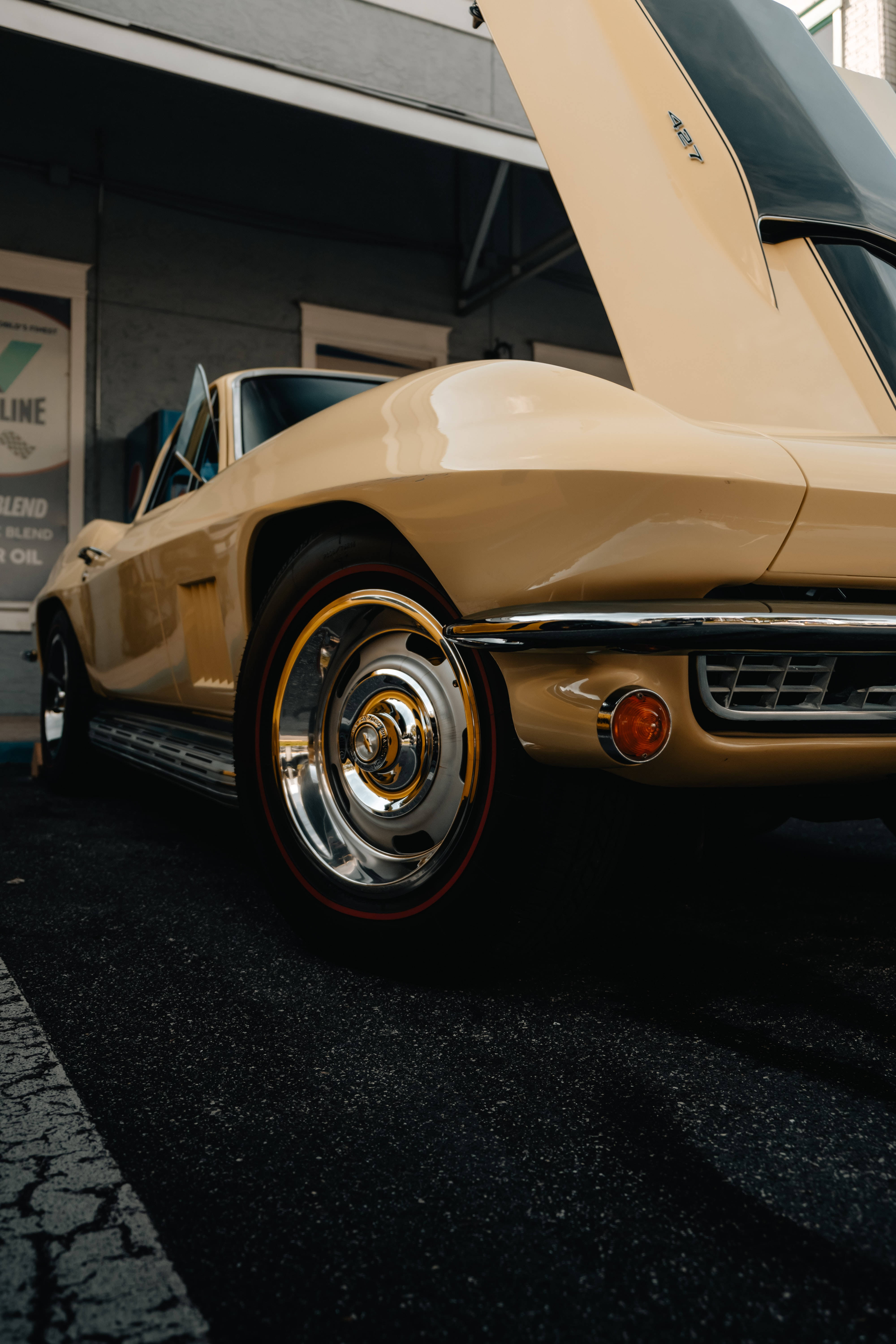 Chevrolet 桌布 壁紙 — 低角度拍攝一輛奶油色經典Corvette，引擎蓋打開，停在車庫中。