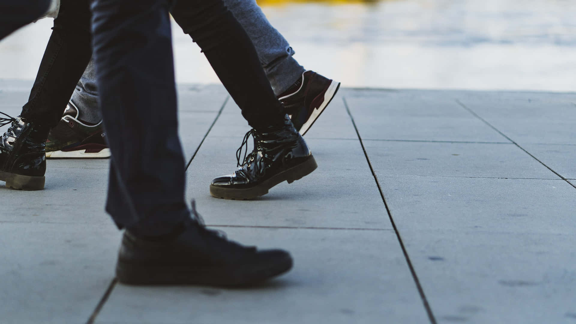 feet 桌布 壁紙 — 低角度拍攝多位行人的腿和鞋子在灰色瓷磚人行道上行走。