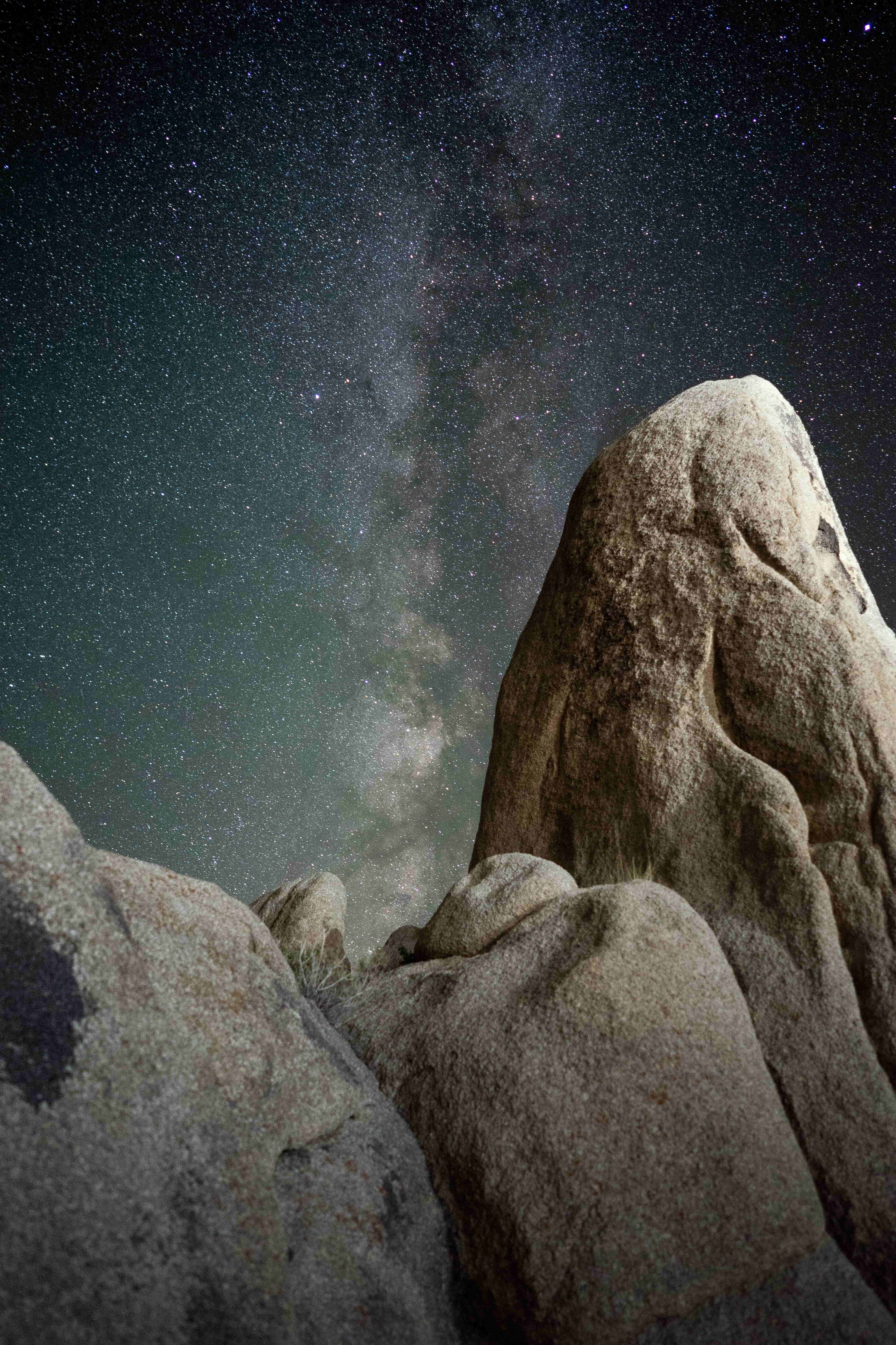 加州 桌布 壁紙 — 低角度拍攝巨大紋理岩石框住銀河系在繁星點點的夜空中發光。