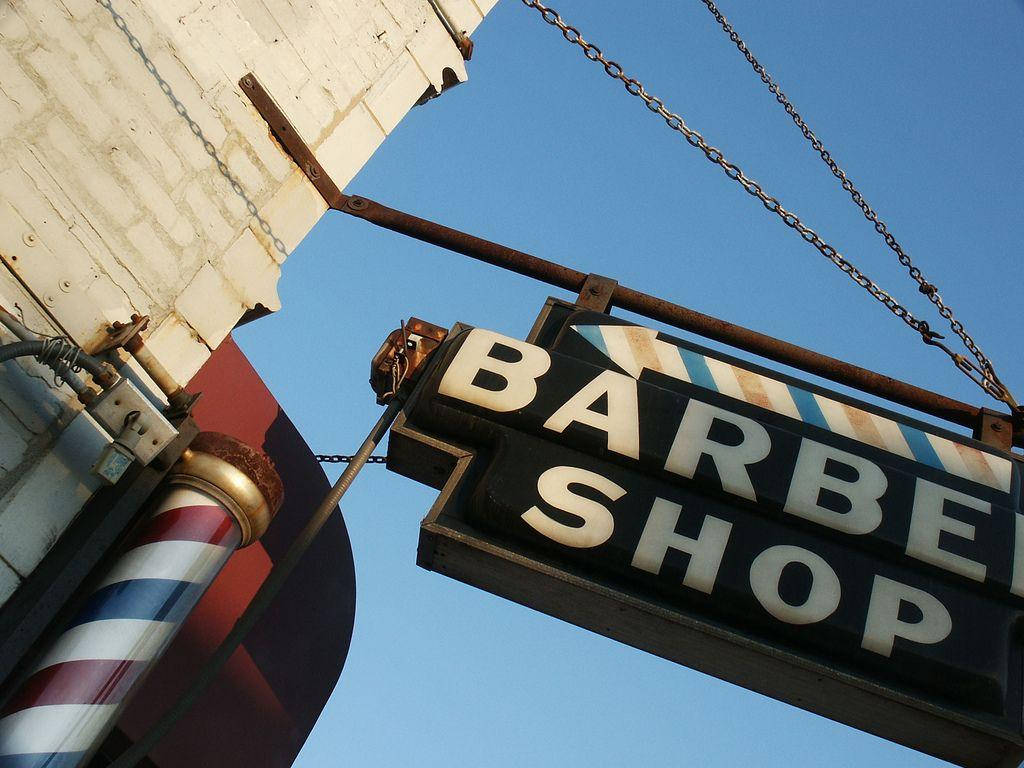 Barber 桌布 壁紙 — 低角度拍攝復古理髮店招牌，經典條紋柱，襯托清澈藍天。