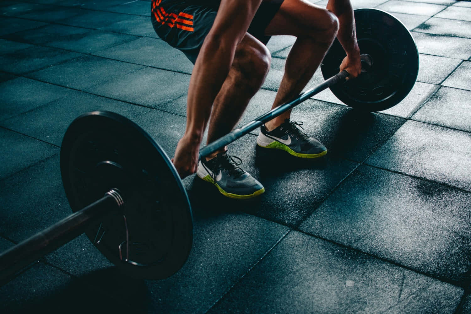 Fitness 桌布 壁紙 — 低角度拍攝捕捉到一個人在昏暗的健身房地板上，在戲劇性的燈光下進行深蹲舉起槓鈴。