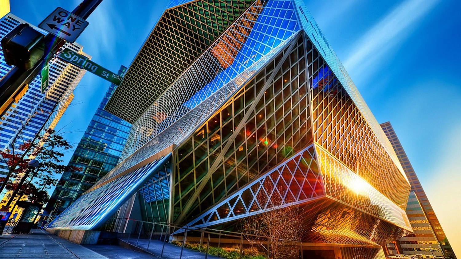 Building 桌布 壁紙 — 低角度拍攝捕捉到一座未來主義的玻璃和鋼鐵建築，反射著金色的夕陽光芒，背景是帶有條紋雲彩的鮮豔藍天。