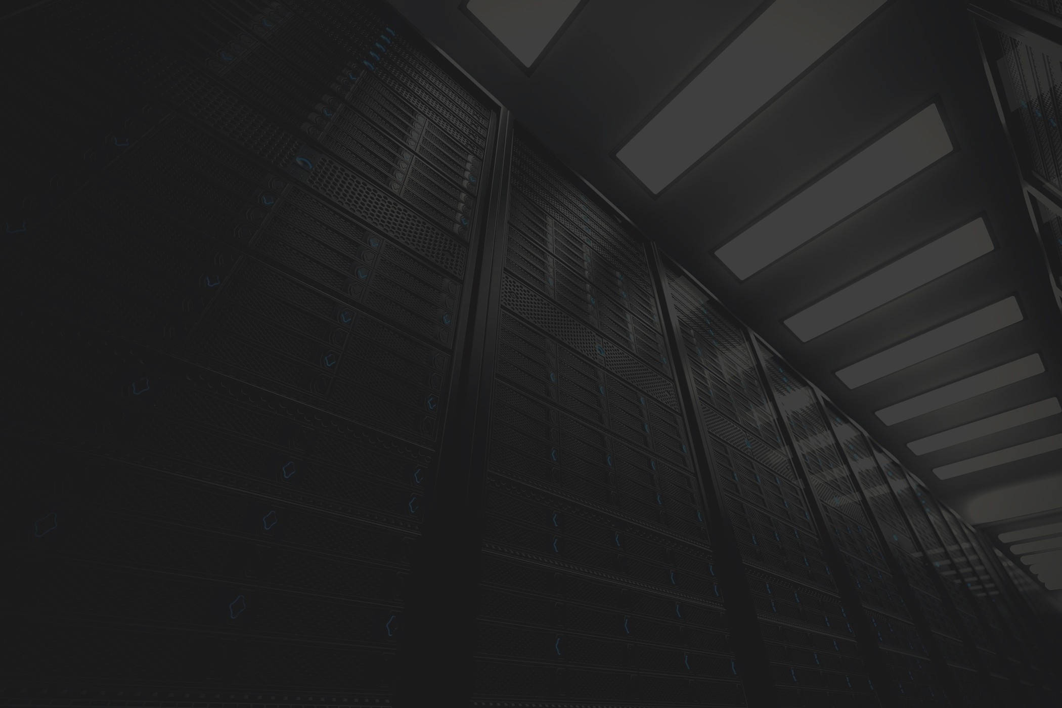Data Center 桌布 壁紙 — 低角度拍攝昏暗資料中心內高聳的伺服器機架，帶有發光的藍色指示燈。