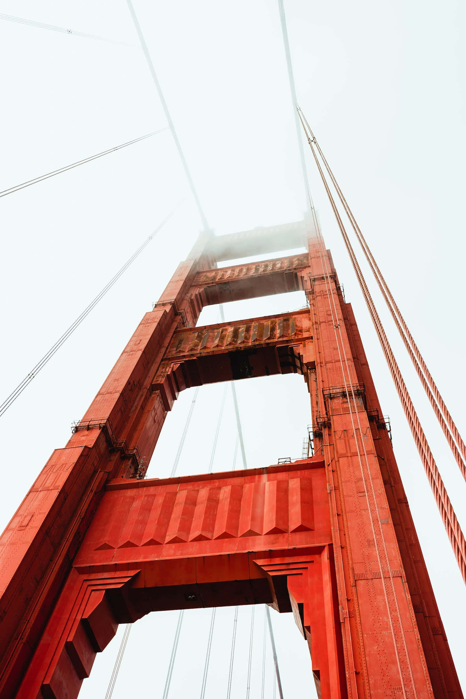 San Francisco Fog 桌布 壁紙 — 低角度拍攝標誌性的紅色金門大橋穿過濃霧天空。