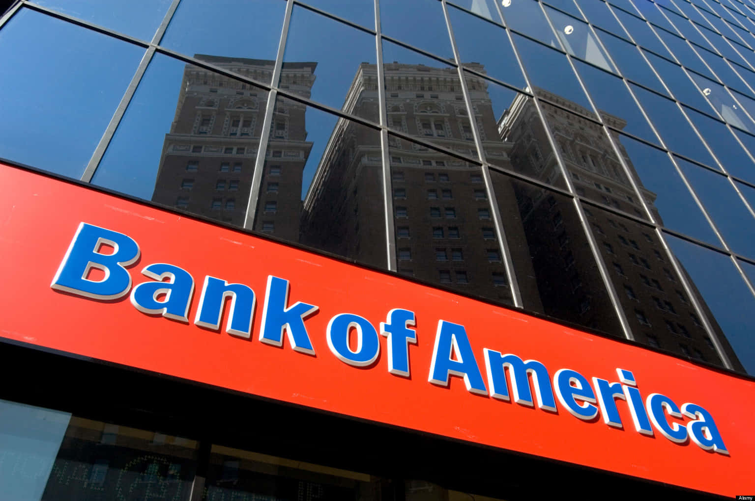 美國銀行 桌布 壁紙 — 低角度拍攝玻璃建築上的 Bank of America 標誌，映照出晴朗藍天下歷史悠久的摩天大樓。