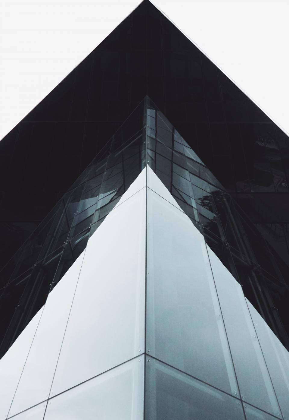 Architecture 桌布 壁紙 — 低角度拍攝現代玻璃摩天大樓尖銳幾何角落，襯以淡色天空。