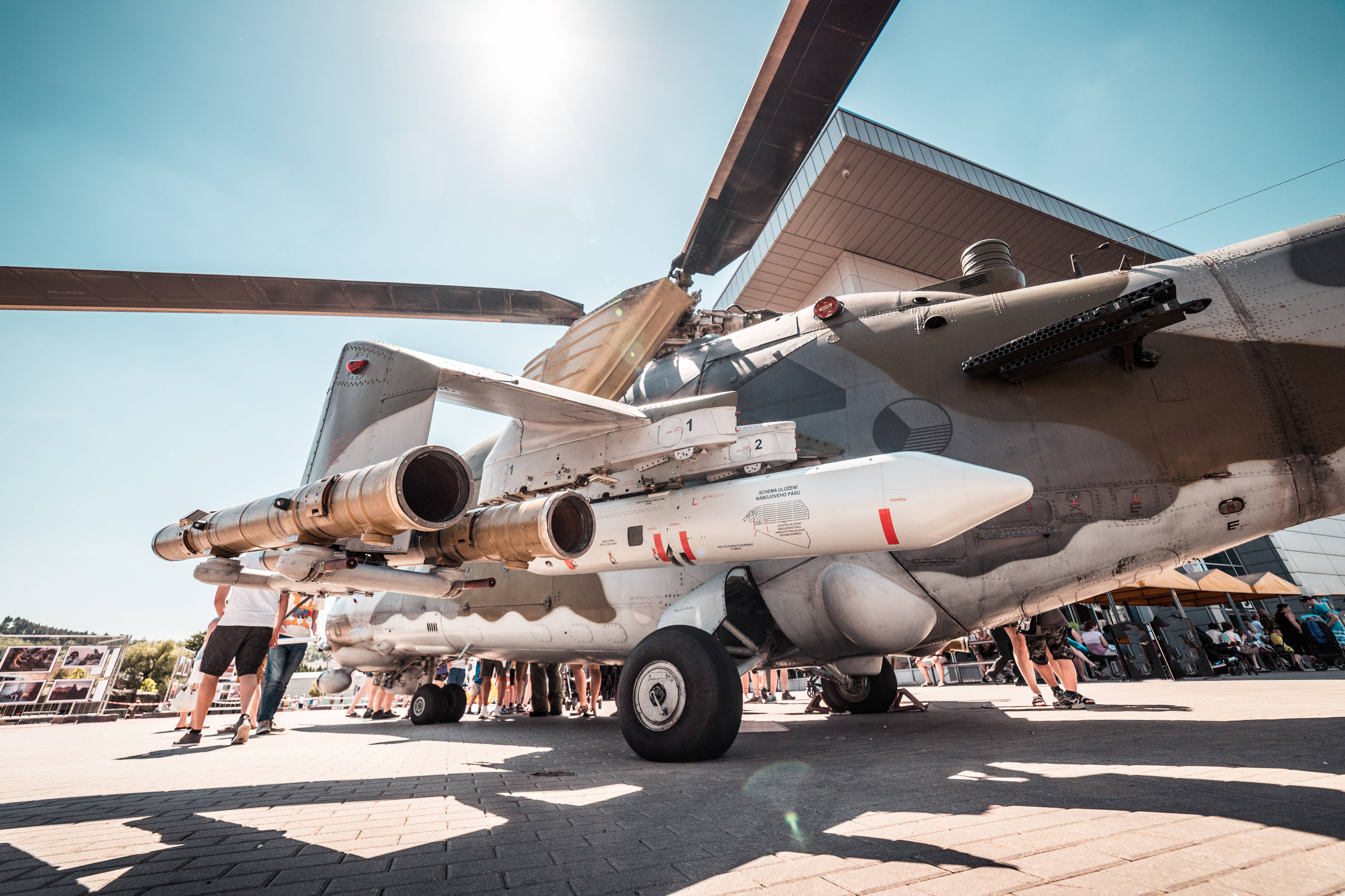 helicopter 4K 桌布 壁紙 — 低角度拍攝的軍用直升機，在戶外航空展上展示飛彈，陽光燦爛。