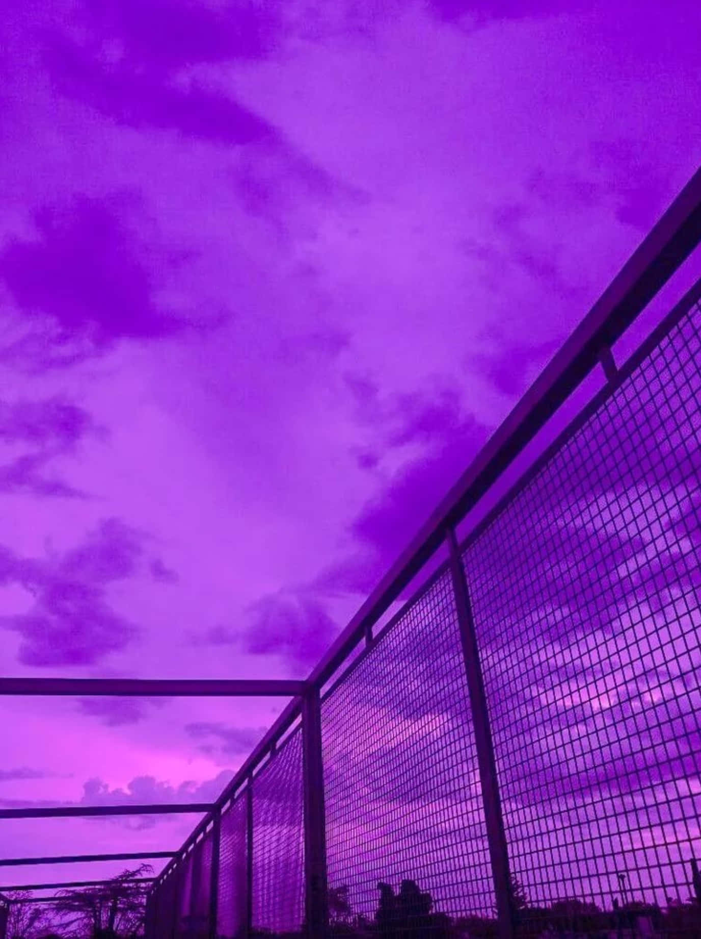 Aesthetic Sky 桌布 壁紙 — 低角度拍攝的金屬圍欄，背景是生動的紫色暮色天空，散落著雲朵。