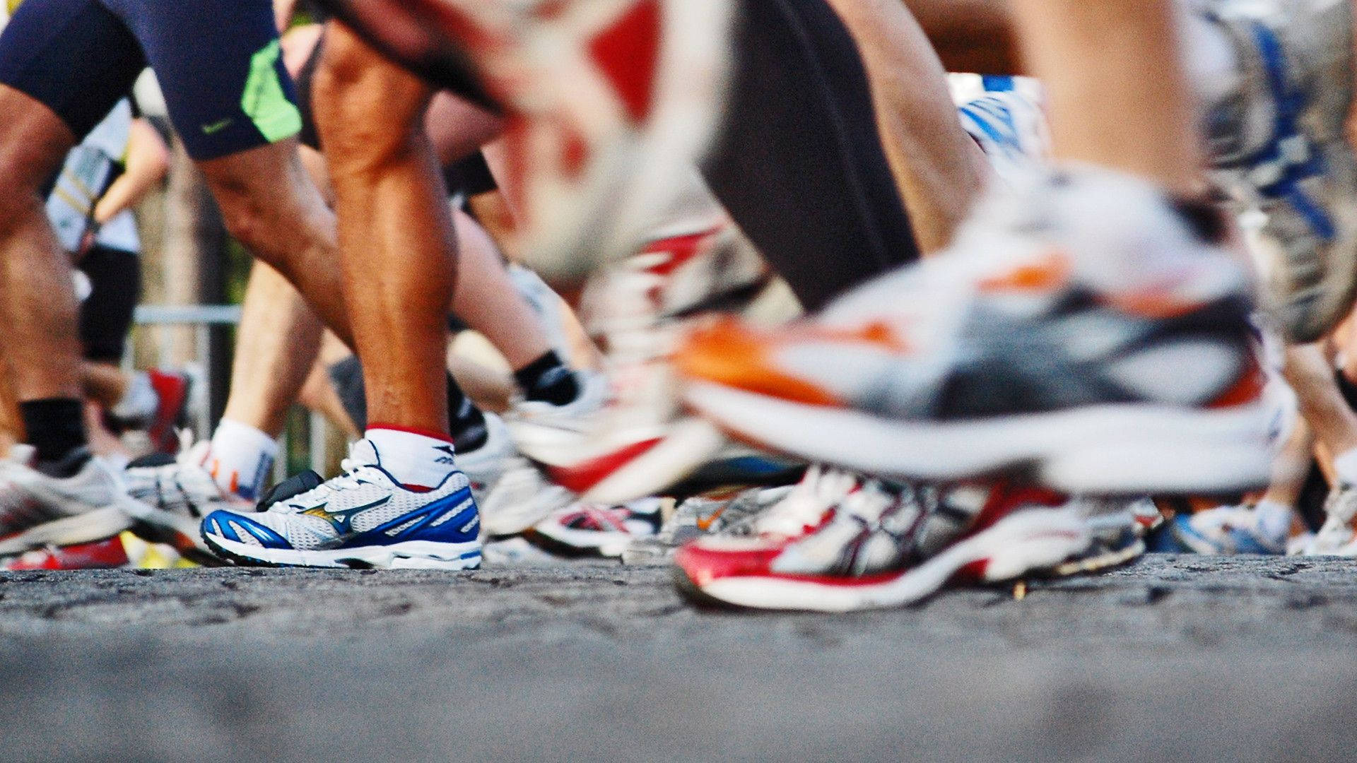 Marathon 桌布 壁紙 — 低角度拍攝跑者雙腿和色彩繽紛的運動鞋在瀝青賽道起跑線上的照片。