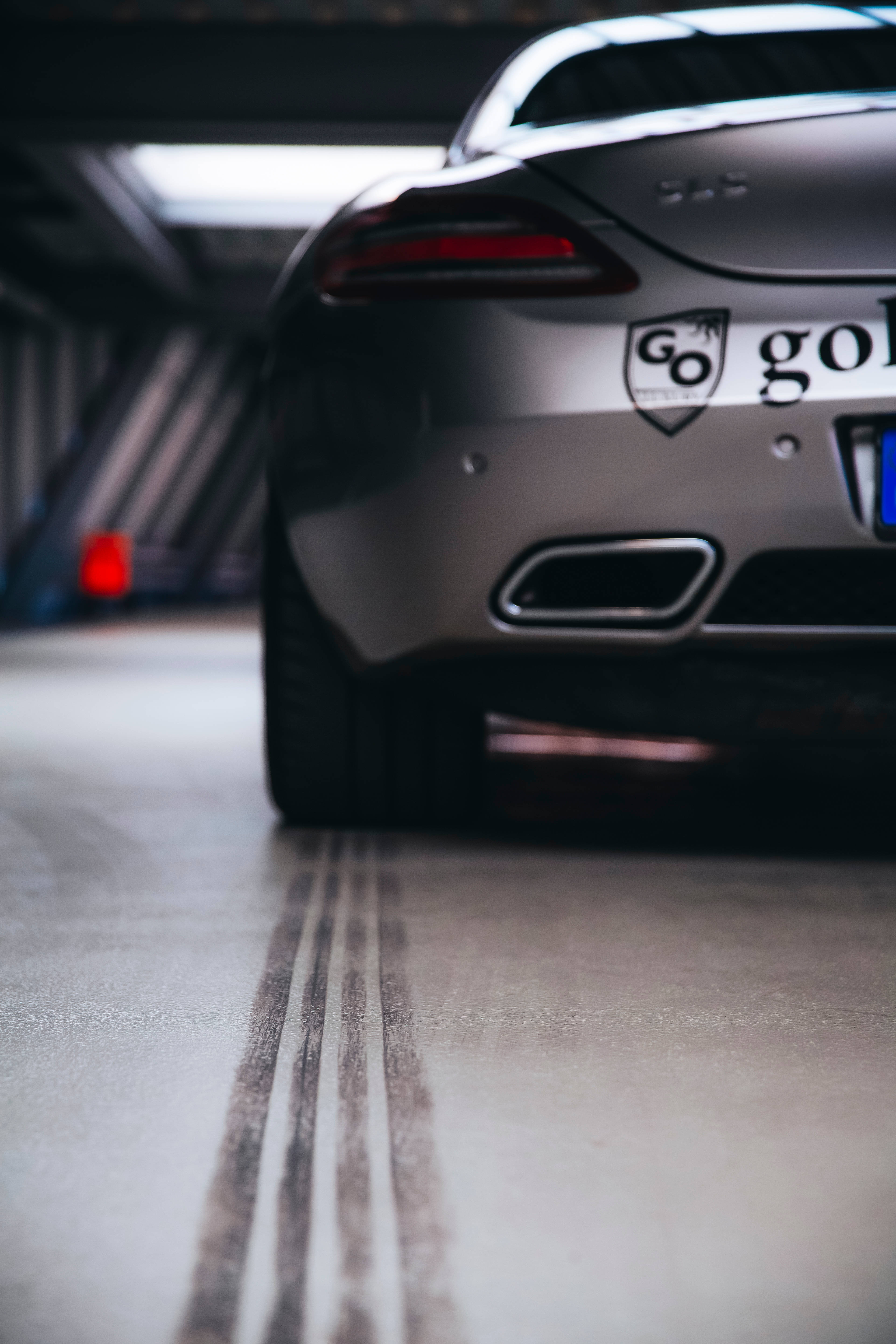Mercedes Amg 桌布 壁紙 — 低角度拍攝銀色跑車尾部，混凝土地板上有輪胎痕跡，車庫光線昏暗。
