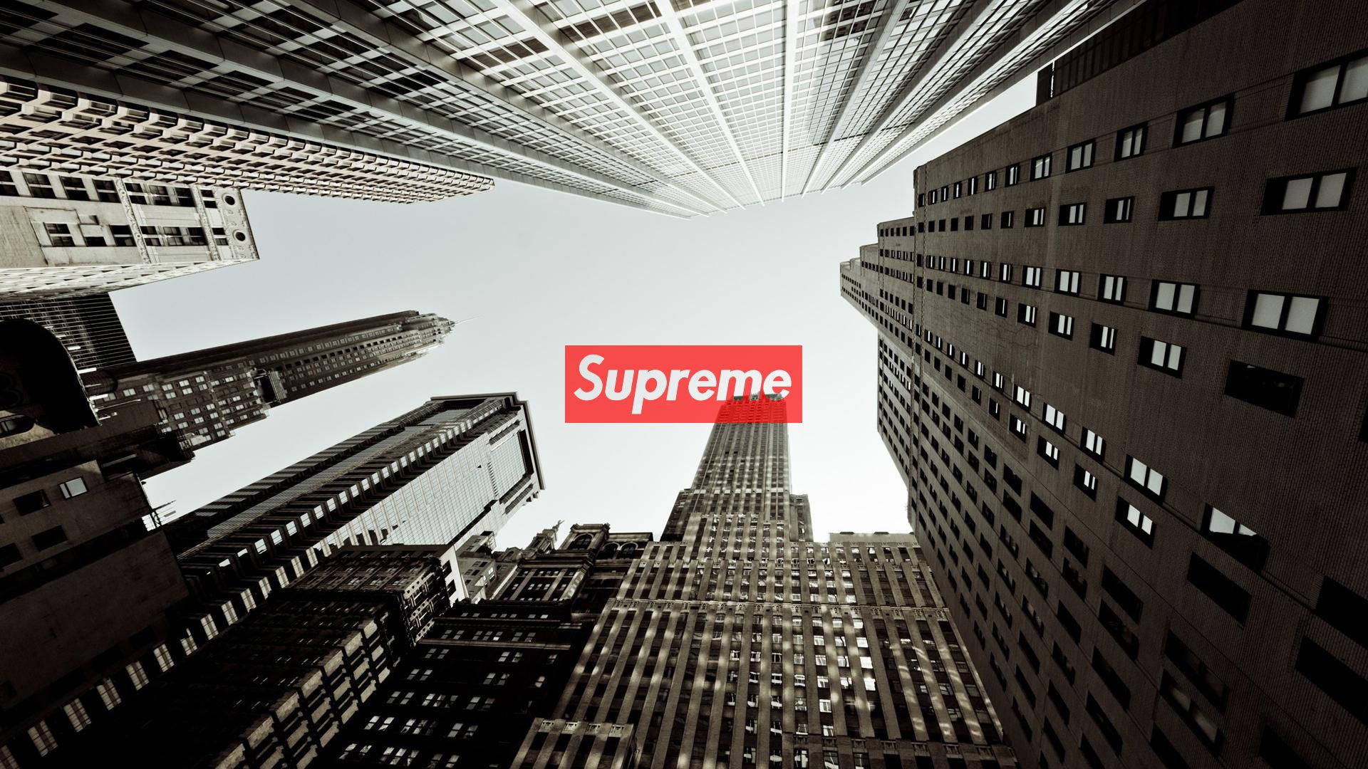 supreme 桌布 壁紙 — 低角度拍攝高聳摩天大樓匯聚向明亮天空，畫面中央有紅色 Supreme 標誌。