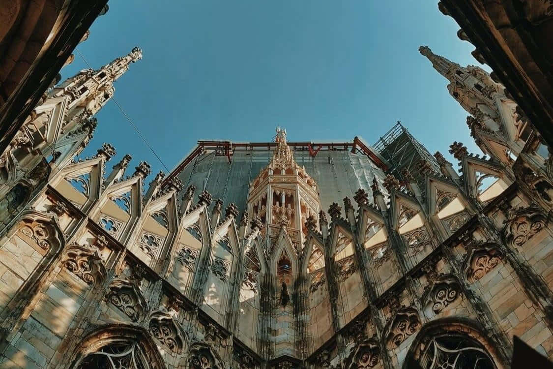 Gothic Architecture 桌布 壁紙 — 低角度視角捕捉到一座大教堂在晴朗藍天下複雜的哥德式建築，並可見修復鷹架。