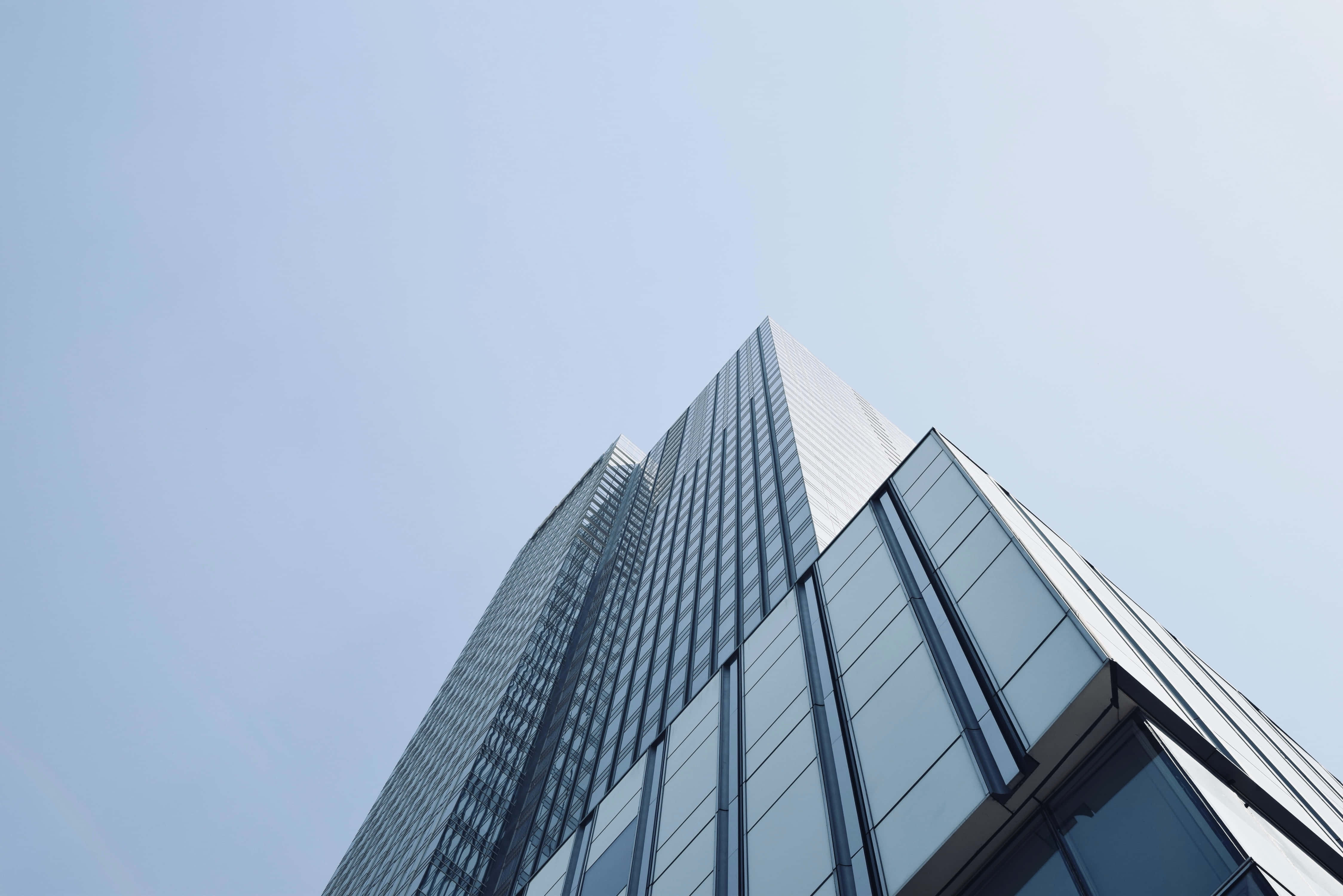 Building 桌布 壁紙 — 低角度觀看一座時尚的玻璃摩天大樓刺穿清澈的淡藍色天空。
